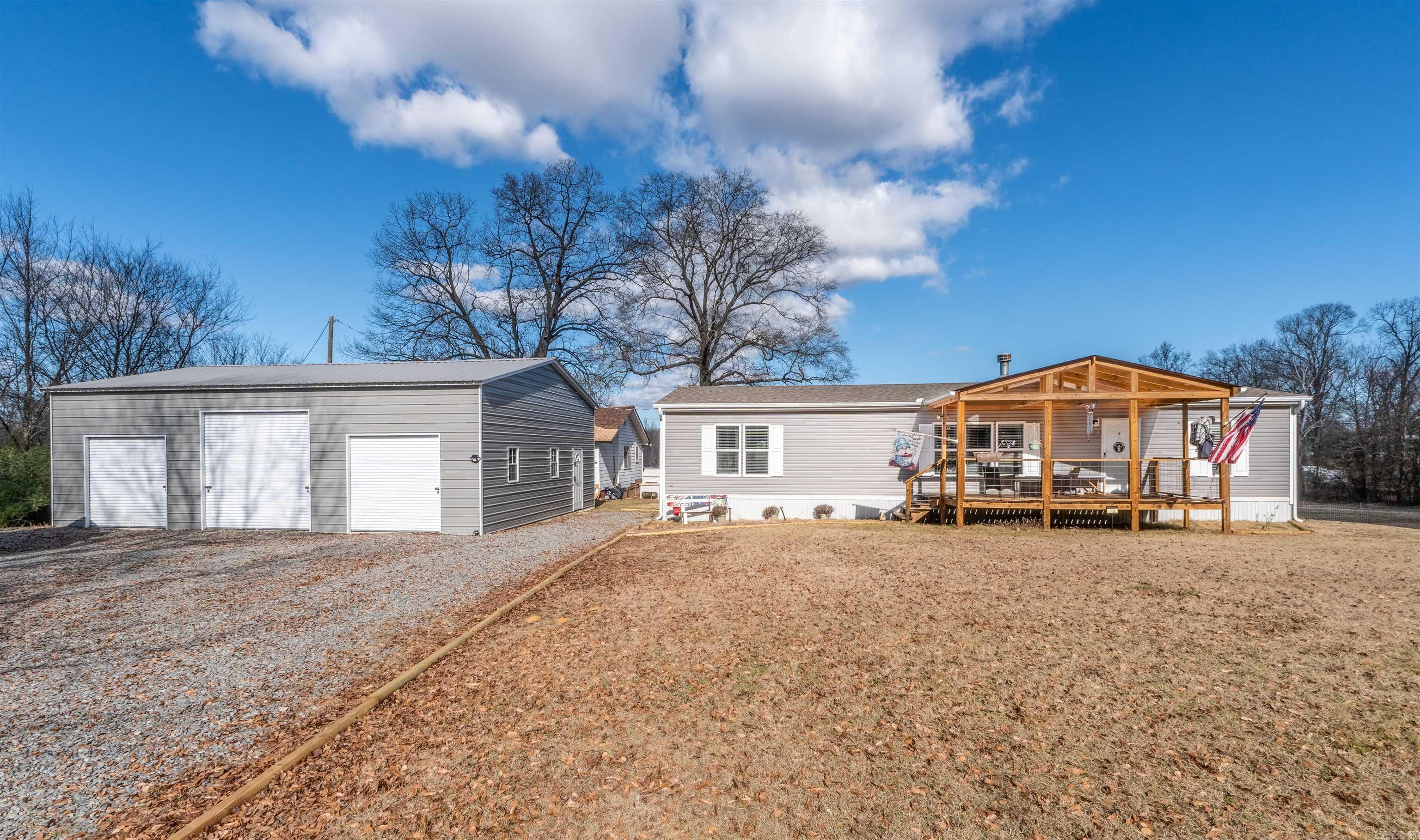 2023 manufactured home on a permanent foundation situated on approximately 10 acres +/- with no restrictions. This 1,600 sq ft home features an open floor plan with a real wood-burning fireplace, front porch, and back deck. Property improvements include a 30x40 detached shop/garage with 3 bays, 30x32 greenhouse, shed, and 3 chicken coops, offering endless possibilities for animals, hobbies, equipment storage, or homesteading. The property is fenced and cross-fenced and borders Greenbrier Creek for added outdoor enjoyment and scenic views. Primary bath features a 72-inch shower and soaking tub. The original approximately 900 sq ft home on the property conveys at no value and could serve as storage, workshop space, or potential additional living space with improvements.