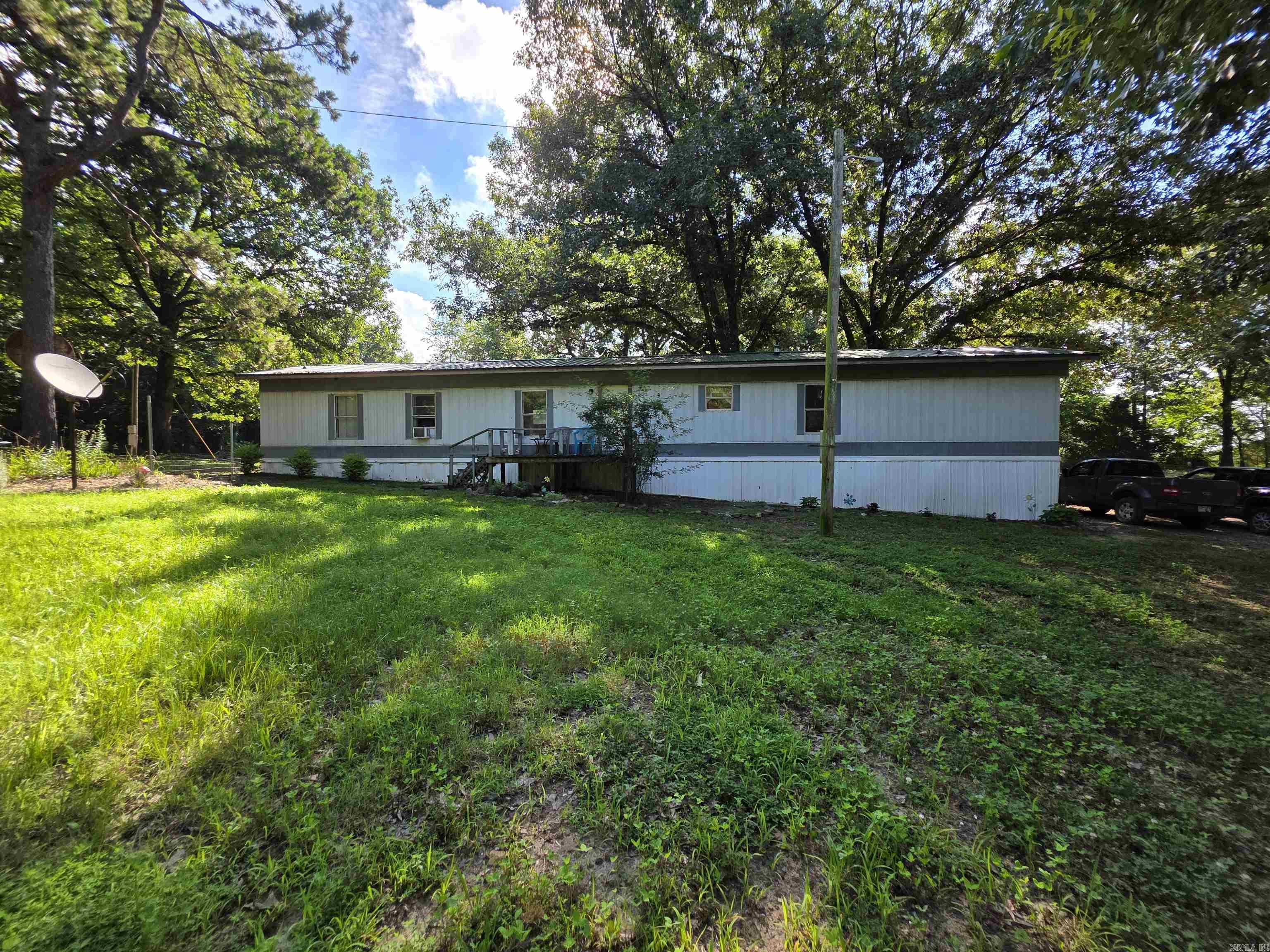3 acres of beautiful shade trees and peaceful mountain views create the perfect country setting just minutes from Mena. Approximately 2 acres are fully fenced and cross-fenced, offering excellent space for animals, gardening, or hobby farming.  The 1999 3-bedroom, 2-bath mobile home features updated interior paint, some updated flooring, and a new roof. A new front porch will be installed soon, adding even more curb appeal.   Outbuildings and improvements include: 8×16 storage building with oversized door 15×20 barn Chicken coop inside a completely fenced yard This property is set up for versatility—mini-farm, homestead, rental, or a quiet country retreat. So many possibilities. Located in Mena, Arkansas. Agents, see remarks.