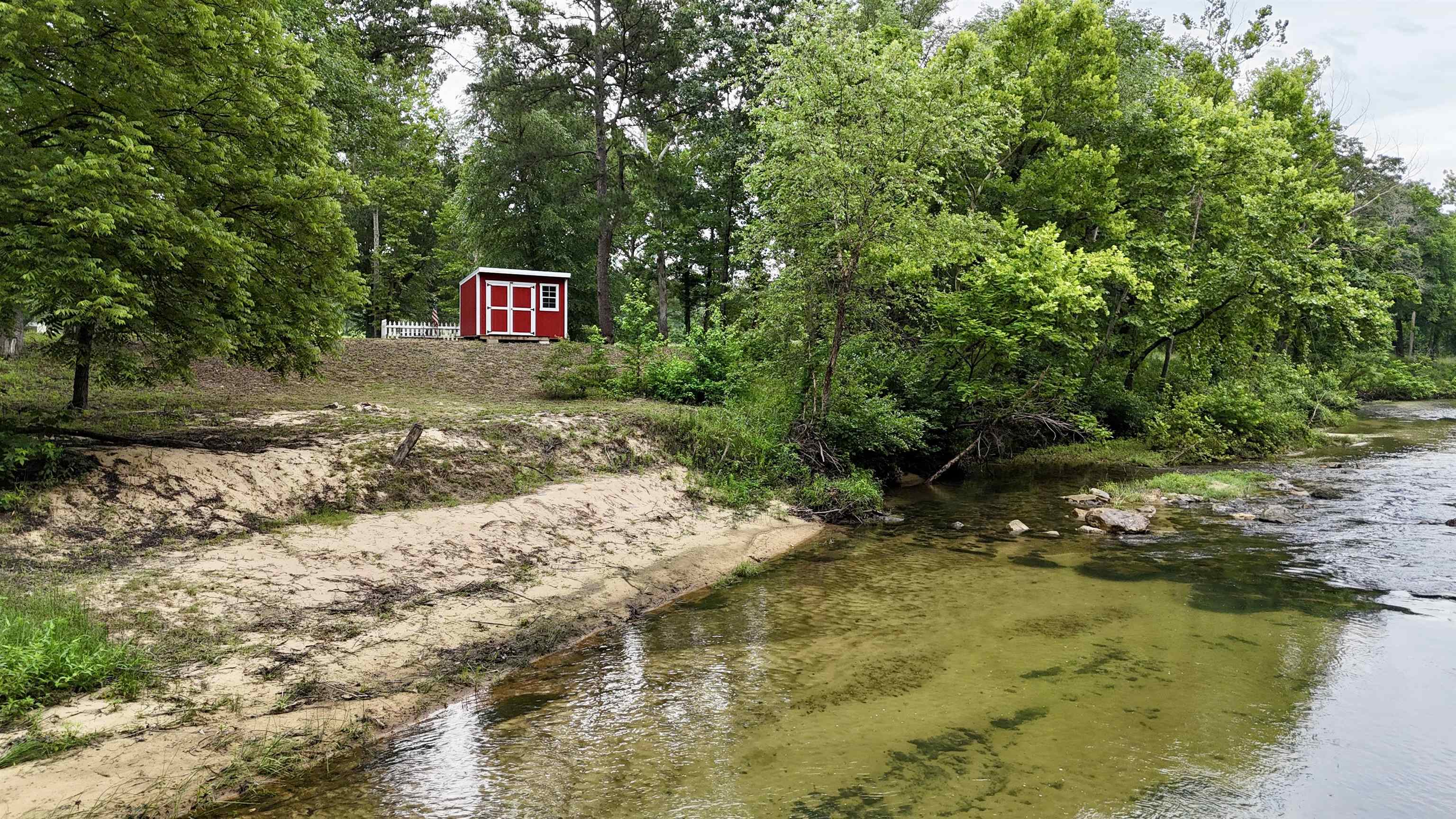 1.74 ACRES WITH CREEK FRONTAGE! Have you been dreaming of owning a piece of property on a year round creek? Property is located on Mill Creek with crystal clear water and sandy beaches! This property has great access down to the water, lots of shade trees, and a storage building that will convey. There is access to electric & Fiber Internet.
