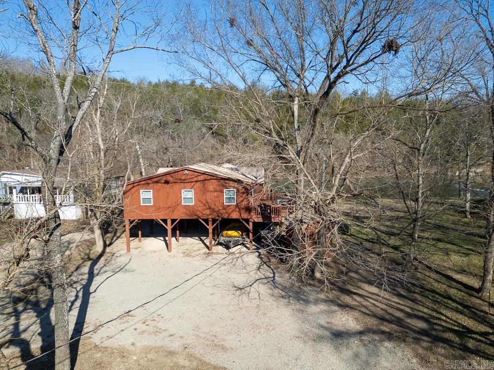 Spring River frontage on approx. 0.4 acres, located midway between Hardy, AR and Mammoth Spring, AR. Property includes two living structures connected by extensive decking. Main house offers 1,484 sq ft with 3 bedrooms and 2 full baths, open kitchen/living area, and eastern red cedar interior walls. Separate 680 sq ft master suite includes 1 bedroom and 1 full bath. Total of 4 bedrooms and 3 full baths.  Outdoor features include a 300 sq ft covered porch, approx. 1,250 sq ft wrap-around wood deck, sun deck on the riverbank, and outbuilding for storage. Spring River is known for trout, bass, walleye, and catfish, and supports abundant wildlife including eagles, herons, ducks, beavers, and otters. Consistent spring-fed flow with frequent morning fog.