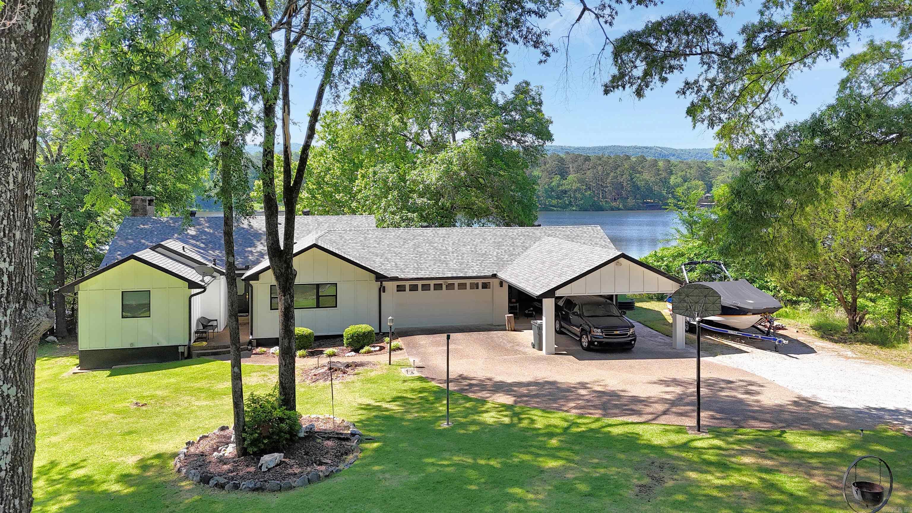 Welcome to your lakefront retreat! This beautifully maintained home has had only two proud owners, and it shows in every thoughtful upgrade throughout. Step inside to discover a main level designed for effortless living. The updated kitchen opens graciously into the dining and living areas, where abundant windows flood the space with natural light and frame those gorgeous lake and mountain views. The primary bedroom features a private en suite bath with large walk-in closet, while a guest bedroom, full bath, and convenient laundry round out the main floor. Head downstairs to find 2 add'l guest bedrooms, full bath, a dedicated office, and a second living area perfect for hosting guests. Outside features a patio and a tiered backyard with multiple decks that cascade down to 98' of lake frontage where you’ll find your covered boat dock and swim dock, making every summer day feel like a permanent vacation. Practical features include new Hardie panel siding, roof, and gutters all installed in 2023, a 2-car garage, and a 4-car carport for all your toys and vehicles. This home delivers the complete lakefront lifestyle package you've been looking for. Call today!