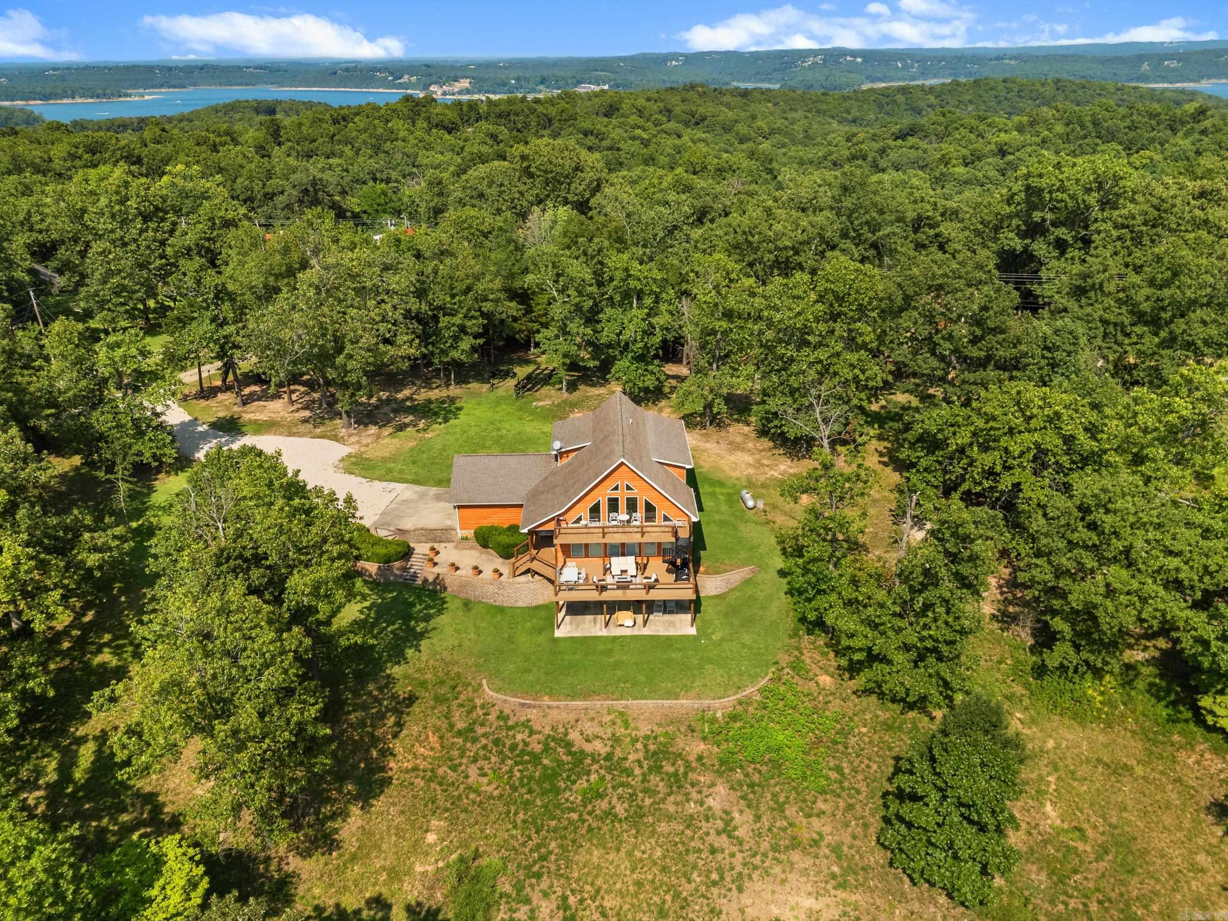 Magnificent 3-level lake home with breathtaking views of Norfork Lake and miles beyond in desirable Robinson Point Estates! Offering over 3,000 sq ft, this exceptional 4-bedroom, 3.5-bath home sits on approximately 2 acres and features an open great room with soaring vaulted wood ceilings, a dramatic two-story stone fireplace, and an impressive wall of windows that perfectly frame the spectacular lake views. The spacious kitchen is equipped with granite countertops and abundant workspace for entertaining. A relaxing loft overlooks the main living area, while the full walk-out basement offers a huge recreation room complete with a kitchenette and second fireplace. Step outside to enjoy the expansive open deck or covered patio, ideal for taking in the scenery. Complete with an attached 2-car garage, this stunning property is just minutes from town and Norfork Lake access, making it the perfect full-time residence or weekend lake getaway.