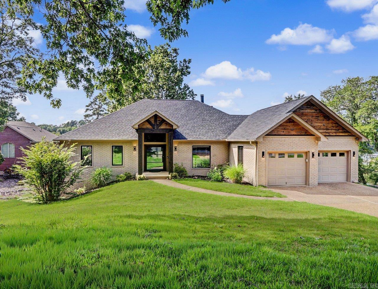 Beautifully updated lakefront home tucked away on a quiet cove on Lake Hamilton, perfect for fishing and relaxing lake days. Enter through a custom glass front door into a spacious open living area and kitchen, ideal for entertaining. Step outside to a generous two-level deck offering multiple seating areas and peaceful cove views. This home offers excellent space for family and guests with four bedrooms, including a primary suite on the main level and three additional bedrooms on the lower level. The lower level also features a second living area and its own deck, creating a comfortable retreat for guests or extended stays. Located in a gated community with many year-round residents, the property provides both privacy and security. Enjoy direct access to a two-slip covered boat dock with a new lift and two jet ski pads. Additional features include a full-house Kohler generator, a new roof installed in 2023, and an elevation certificate on file. The home is not located in a flood zone.
