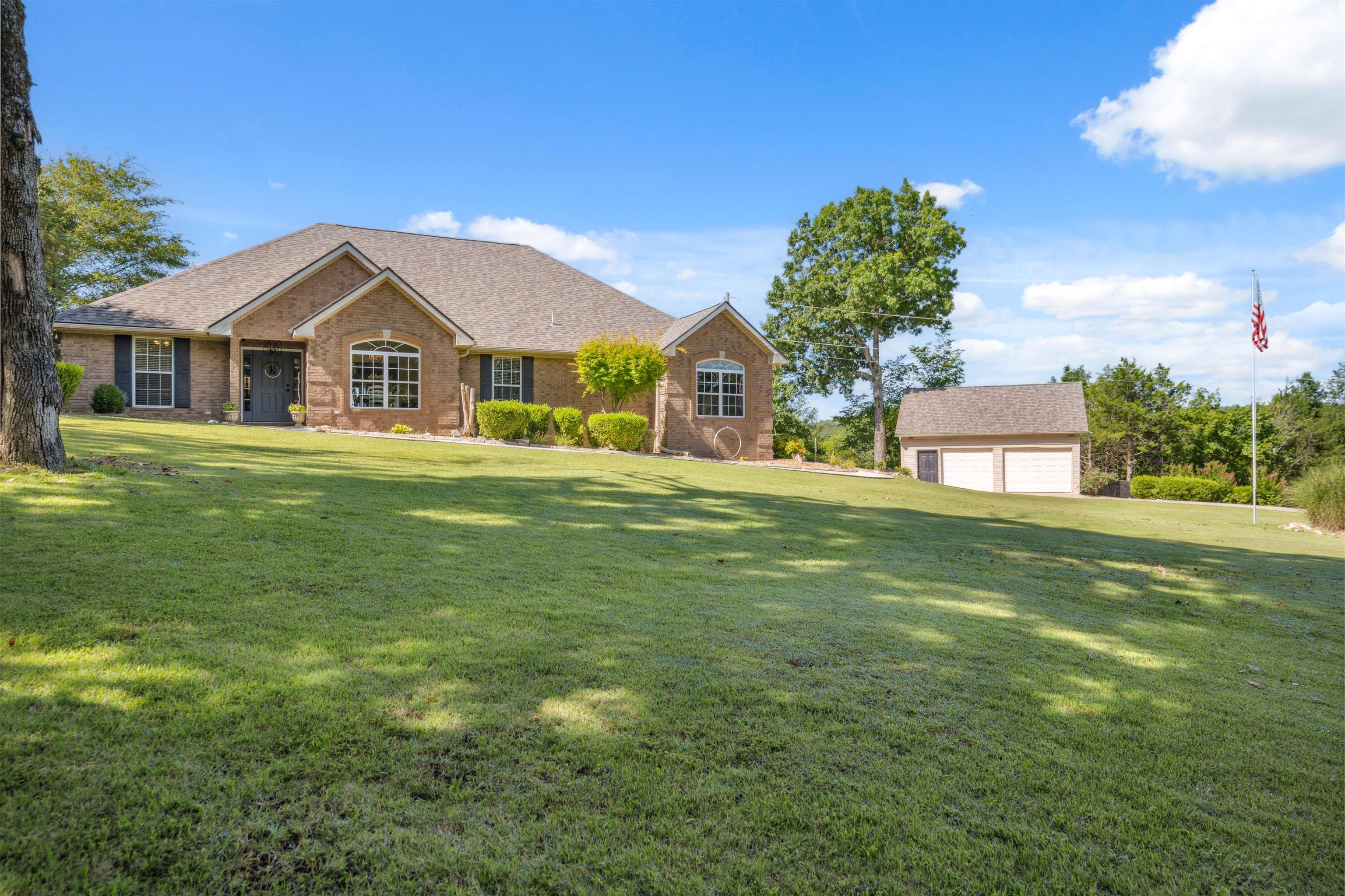 Experience the ultimate river-view retreat with this pristine, all-brick masterpiece perched on a breathtaking bluff overlooking the Spring River. Situated on three expansive lots containing 5 acres m/l, this 2,081 sq. ft. all electric home has been perfectly renovated with a keen eye for detail. The stunning interior is defined by soaring vaulted wood ceilings with recessed lighting and a beautiful gas log fireplace that anchors the living space. Abundant natural light floods the open-concept kitchen, which boasts granite countertops, stainless steel appliances, and a breakfast bar, plus a separate dining area. The primary suite offers spa-like luxury with dual vanities and a custom-tiled walk-in shower and tub combo and large walk-in closet. While the third bedroom lacks a closet, its generous size is perfect for an armoire, a phenomenal home office, or a private library. Outside, a massive deck spans the length of the home, offering unparalleled panoramic views and total serenity. Complete with a detached garage/workshop, this well-appointed home combines sophisticated style with the peace of nature. This is bluff-top living at its finest!