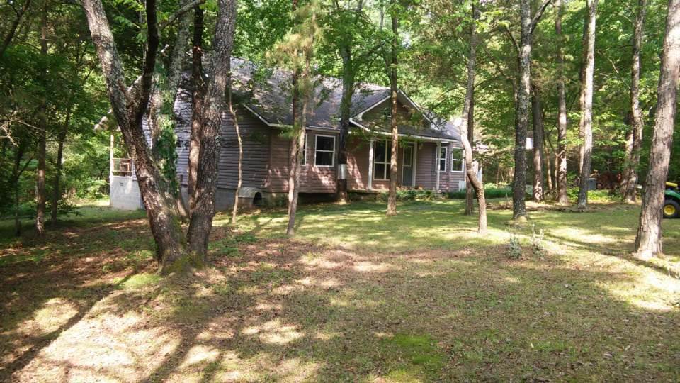 This home has it all, privacy in the center of town, secluded on 5 acres of wooded land, 0.7 mile from the schools, 1/2 mile from Walmart. A split bedroom floor plan: 2bed/1bath opposite the Master Suite, separated by the Great Room consisting of living, dining and kitchen areas with a woodburning stove centrally located and able to heat entire house. Oversized attached two car garage with workshop space, huge covered back porch, deep soaking bathtubs, lots of built in shelving, vaulted ceiling, and more!