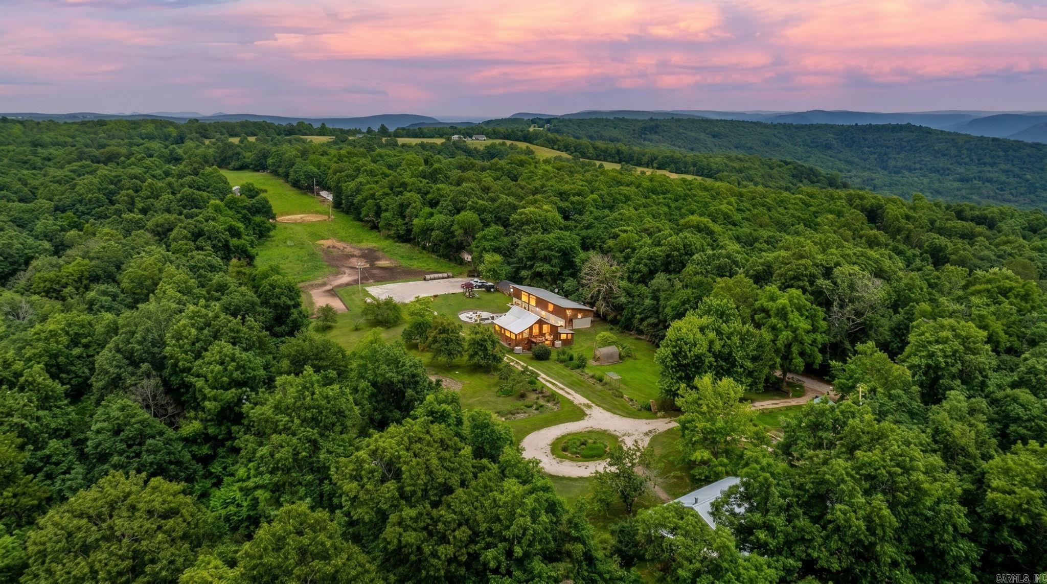 Set in the Ozark Mountains near Jasper and the Buffalo National River, this 18-acre retreat brings together privacy, character, and exceptional flexibility.  The property features a 3-bedroom, 1-bath farmhouse-style cabin, a spacious community gathering hall with a large kitchen, a converted barn with additional living and sleeping quarters, and two separate sleeper cabins for guests or retreat-style accommodations. Outdoor features include a pond, fenced horse pasture, established garden space, fruit trees, wooded surroundings, and multiple areas for gathering, relaxing, and enjoying the land. The 5057 John Deere Tractor and Zero Turn Mower are included in the sale.   Located minutes from Jasper’s town square, Buffalo River recreation, and nearby natural springs with community access, the setting supports a range of uses including a private getaway, homestead, retreat property, hobby farm, or potential short-term rental, subject to buyer verification. A distinctive Ozark property combining rustic charm, usable acreage, and a lifestyle rooted in land, community, and outdoor recreation.