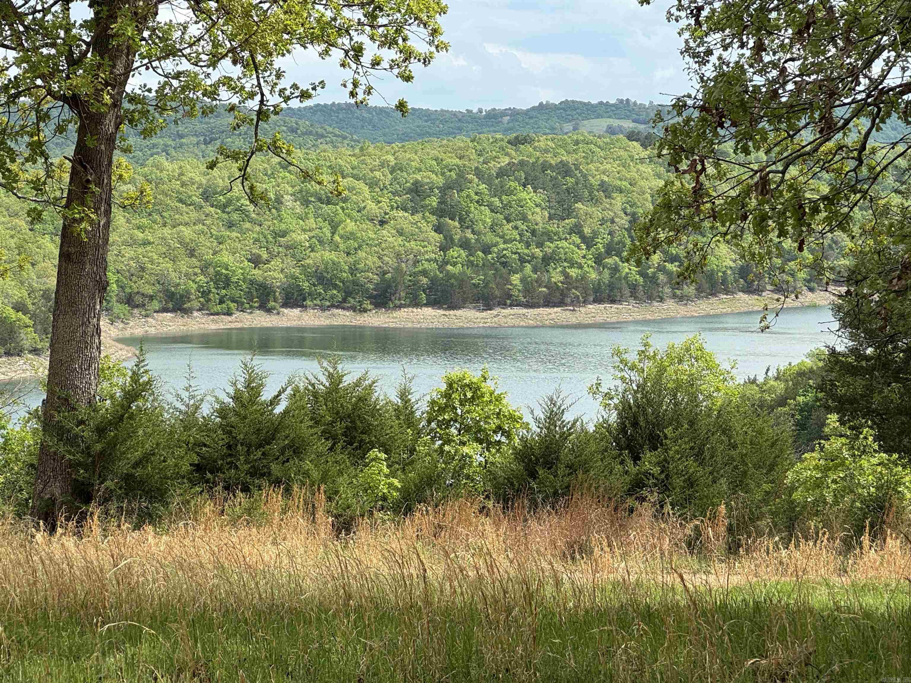 Enjoy breathtaking, year-round views of Bull Shoals Lake from this beautifully updated home, nestled on 5 acres M/L with direct access to the lake just down the road. The property borders the government strip, offering added privacy and serenity. Inside, you'll find two generous suites, each with its own full bath and large closets, plus an oversized laundry room with a convenient 1/2 bath and abundant storage. The spacious country-style kitchen features plenty of cabinetry, ideal for home cooking. Relax on the front porch with stunning lake views, or unwind in the screened-in back porch, perfect for outdoor dining. Recent upgrades include a new metal roof, back porch, and front steps. Additional features include a storm shelter, two sheds, and hardwood floors throughout, with ceramic tile in the bathrooms. This fully furnished home offers 1509 SQ FT of living space and is priced at $370,000 an exceptional opportunity for lakeside living!