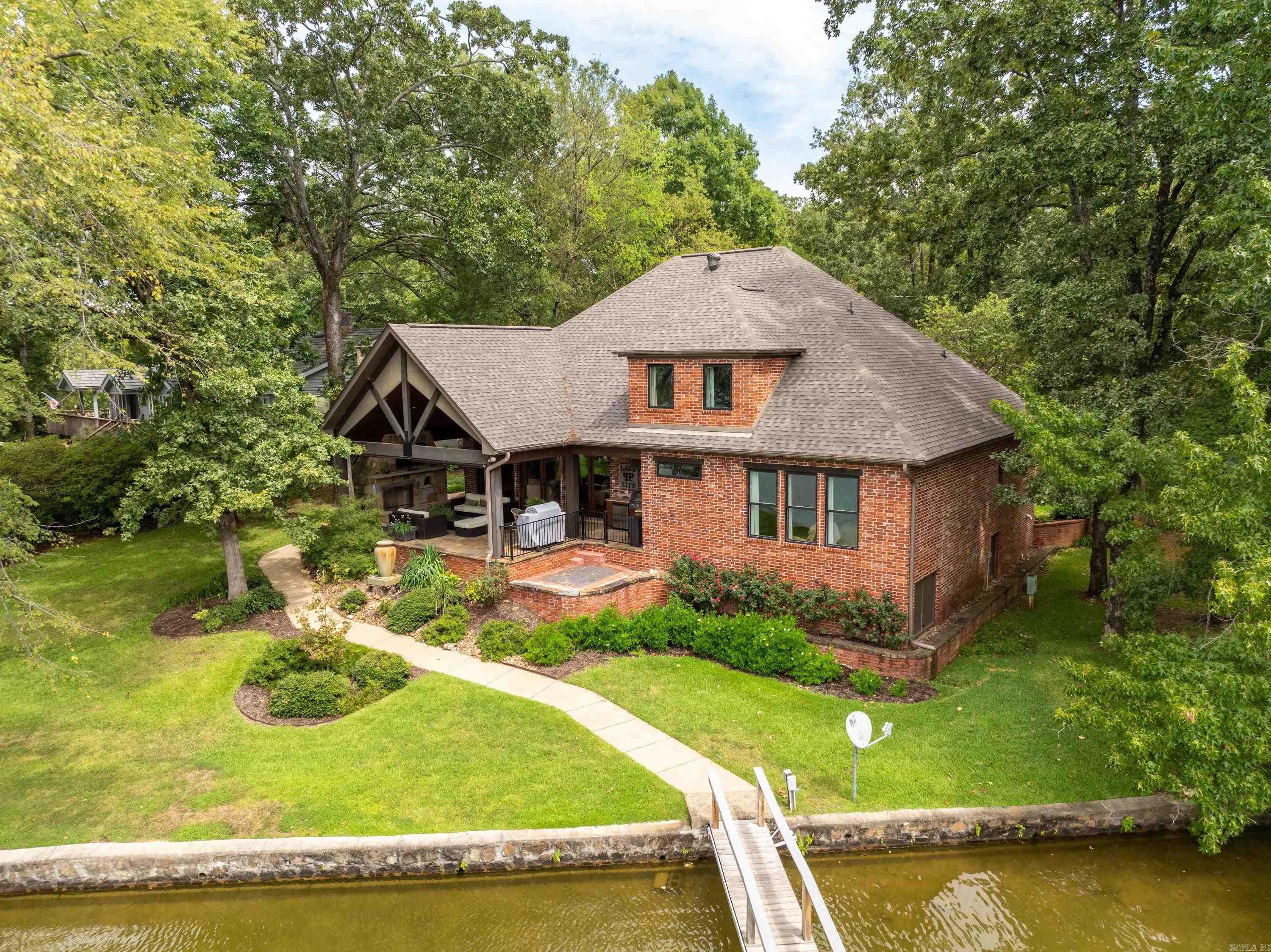 Welcome to 480 Bayshore Drive, a picturesque lakefront gem in the serene landscapes of Hot Springs, Arkansas. This inviting retreat seamlessly blends modern comfort with natural beauty, offering the perfect getaway for both relaxation and recreation. Nestled on a spacious lot on Lake Hamilton, this home features breathtaking water views and a private dock for boating, fishing, and swimming. The open-concept floor plan is bathed in natural light, with expansive living areas, a cozy fireplace, and a vaulted wood ceiling that enhances the home's charm. The chef’s kitchen boasts high-end appliances, granite countertops, and a large island, ideal for casual dining and entertaining. With 4 generously sized bedrooms and modern bathrooms, the primary suite stands out as a peaceful sanctuary overlooking the lake. Step outside to a stunning flagstone patio, complete with a fireplace, built-in pizza oven, and outdoor kitchen, perfect for entertaining or unwinding in a picturesque lakeside setting. Located in a highly desirable neighborhood, this home offers both a peaceful retreat and convenient access to dining, shopping, and recreational activities.