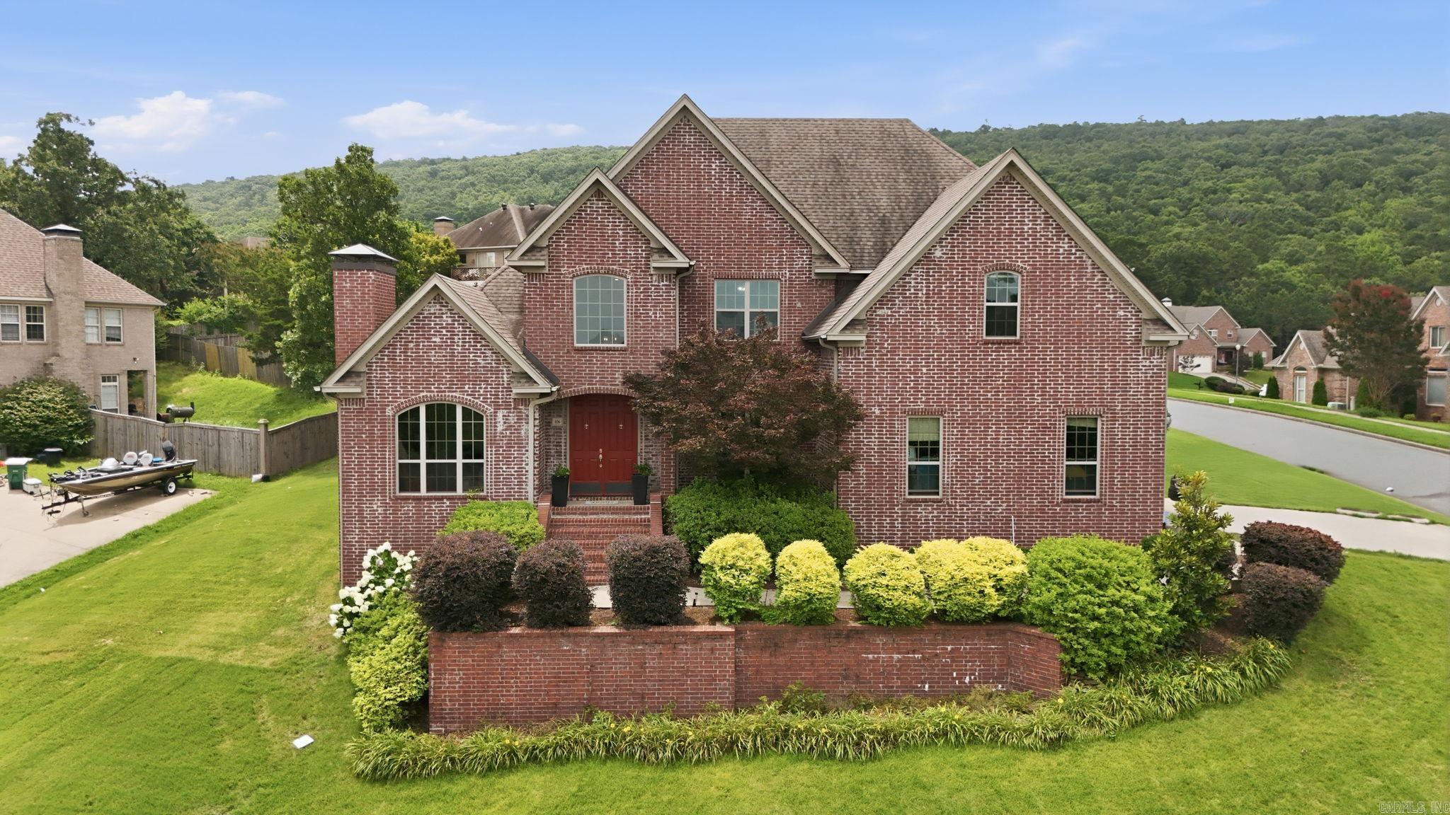 Tucked into Challain Place in the heart of Chenal Valley, this all-brick two-story captures sweeping Pinnacle Mountain views from a beautifully landscaped corner lot. Designed for everyday comfort and easy entertaining, the main level centers on a light-filled great room that flows into the island kitchen—granite counters, double ovens, stainless appliances, and breakfast-bar seating—plus a sunny breakfast nook. A private main-floor primary suite offers dual vanities, a soaking tub, separate shower, and an oversized walk-in closet. A vaulted home office with a gas-log fireplace and a formal dining room with butler's pantry round out the downstairs. Upstairs, three roomy bedrooms (one en-suite, two sharing a Jack & Jill with separate vanities) join a versatile bonus room for work, play, or guests. A drop-zone laundry connects to the 2-car garage, now fitted with two EV chargers. Sprinkler-fed landscaping, generous storage, and a short stroll to the community pool and Chalamont Park complete the package. A true Chenal gem—schedule your showing today!