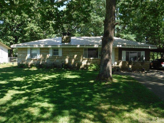 MUST see this amazing setting. Enjoy the Beautiful spacious back yard from your covered screen porch.  Quality wood flooring along with the authentic fireplace make the living room desirable. Kitchen has been updated with newer counter tops and lighting.  Home has separate dinning space plus Additional room ideal for an office. Extra concrete for plenty of parking.   Outside storage building with Electricity