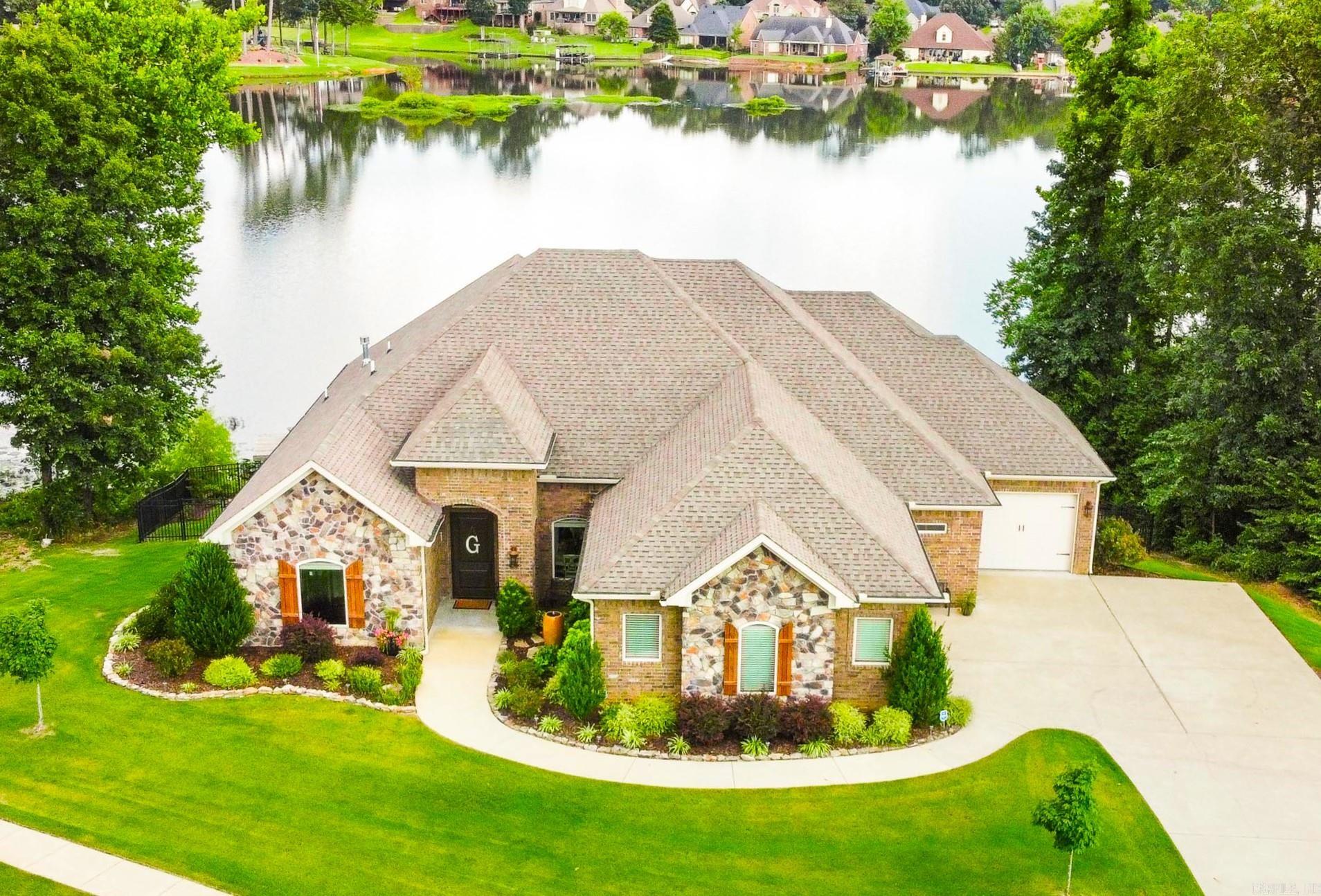 Discover the epitome of lakeside luxury at this stunning custom home nestled on the shores of Hurricane Lake. Designed for seamless single-level living, the residence features 4BR and 3BA on the main level. 12-foot ceilings adorned with wood beams and expansive walls of windows that frame captivating lake views. A striking stone fireplace anchors the living room, while the gourmet kitchen is equipped with an island boasting a built-in wine rack, a stone vent hood, and a walk-in pantry. The adjoining breakfast area and formal dining room provide ample space for entertaining guests. The primary suite is a serene sanctuary with a bay window overlooking the water, a double-sided fireplace, and a generously sized walk-in closet. Additional bedrooms offer huge closets and hardwood floors. Mudroom with built-ins and spacious laundry room. Downstairs, a versatile bonus room includes a wet bar and media room (or potential 5th bedroom), accompanied by a storage room featuring a storm shelter. Outside, the expansive fenced backyard is complete with a picturesque gazebo, sprinkler system, retaining wall, storage room, and a private dock! Lot is very private with woods on either side!