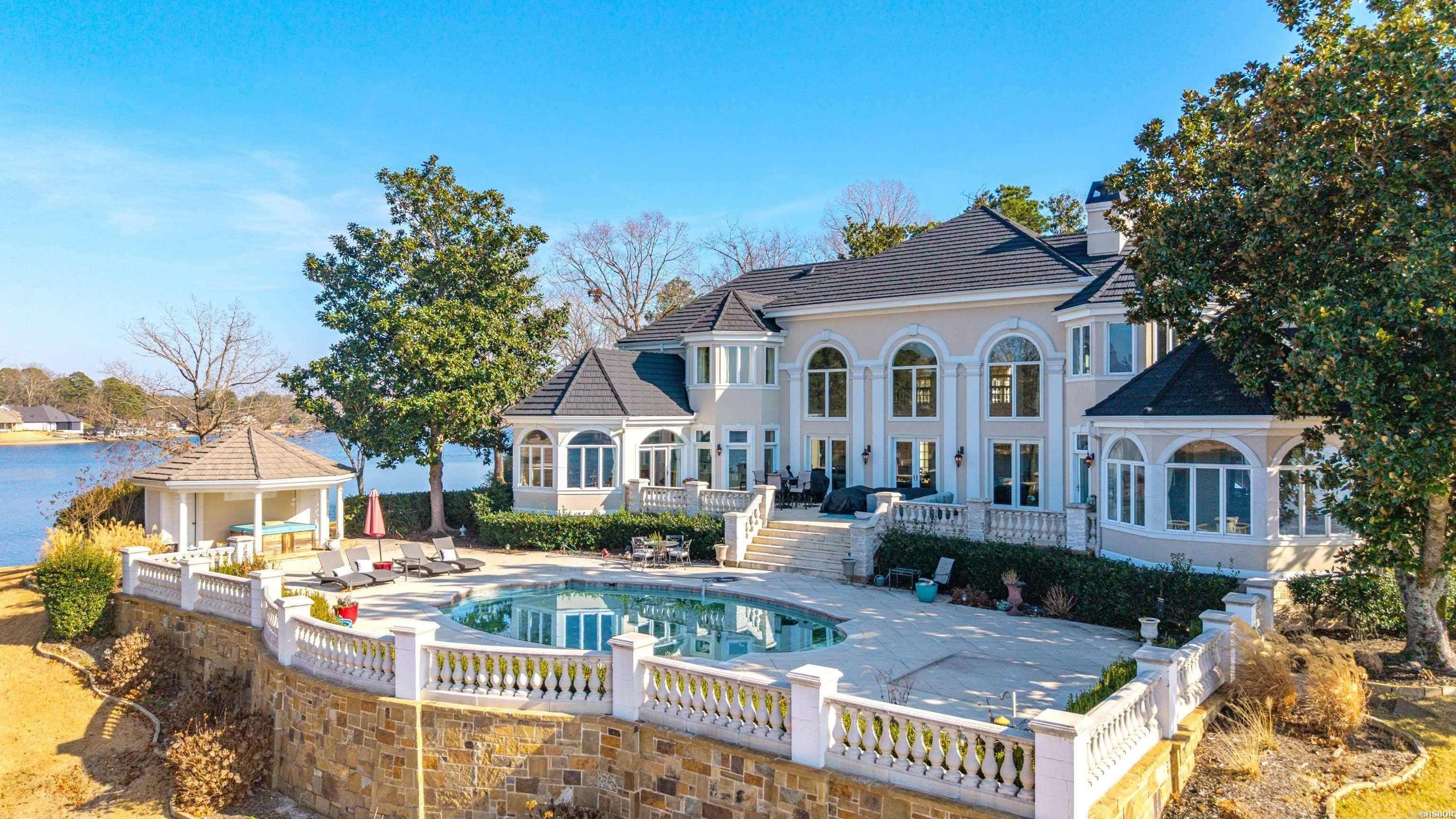This extraordinary lakefront estate represents the pinnacle of luxury living in Hot Springs and is truly as good as it gets on Lake Hamilton. Situated on premier point lots within the highly coveted Driftwood Subdivision, this remarkable property offers an unparalleled combination of size, privacy, craftsmanship, and breathtaking waterfront presence. Encompassing approximately 7,815 square feet of meticulously designed living space, the home is a masterwork of architectural excellence, where superior construction quality and exceptional attention to detail are evident at every turn. Boasting over 1,000 feet of pristine Lake Hamilton frontage, the estate provides sweeping panoramic water views and an unmatched sense of exclusivity. A private, gated entry leads to the residence. Huge Living/Dining area with expansive 22 ft. ceilings and unmatched views of Lake Hamilton. The master suite was thoughtfully placed on the main floor for privacy and convenience. This suite features his/her closets, Exercise room, study/sitting room... CONT'D in agent remarks ...