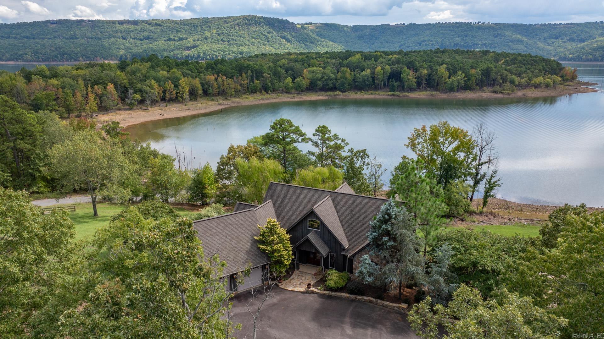 Escape to this stunning LAKEFRONT retreat on GREERS FERRY LAKE in Arkansas with 2 large lots and a boat launch just behind the home. With space to sleep your family and friends and store your lake toys, this home is perfect for seeking serenity and adventure. This expansive home has access to the patios and a view from every bedroom and both living spaces with 2 levels of windows framing the panoramic views or the water. Imagine waking up to the glistening water, spending you days boating, fishing, or simply relaxing by the shore.  This rare find is ideal for family getaways, a corporate retreat, or your dream full-time residence.