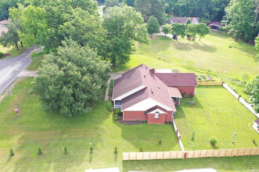 Nestled on 2± acres of level, usable land, this charming one-level brick home blends comfort, privacy, and practicality. A fenced backyard offers plenty of room for pets, play, or gardening, while the expansive lot provides space to add a large man cave, workshop, or additional outbuilding if desired.  Inside, you’ll find bamboo flooring, fresh updates throughout, and a cozy wood-burning fireplace that anchors the living space. The primary suite features his-and-her walk-in closets, giving you the storage everyone wishes they had.  A two-car garage connects to a dedicated workshop, perfect for hobbies, tools, or extra storage. Out back, a covered patio creates an ideal spot for relaxing or entertaining year-round.