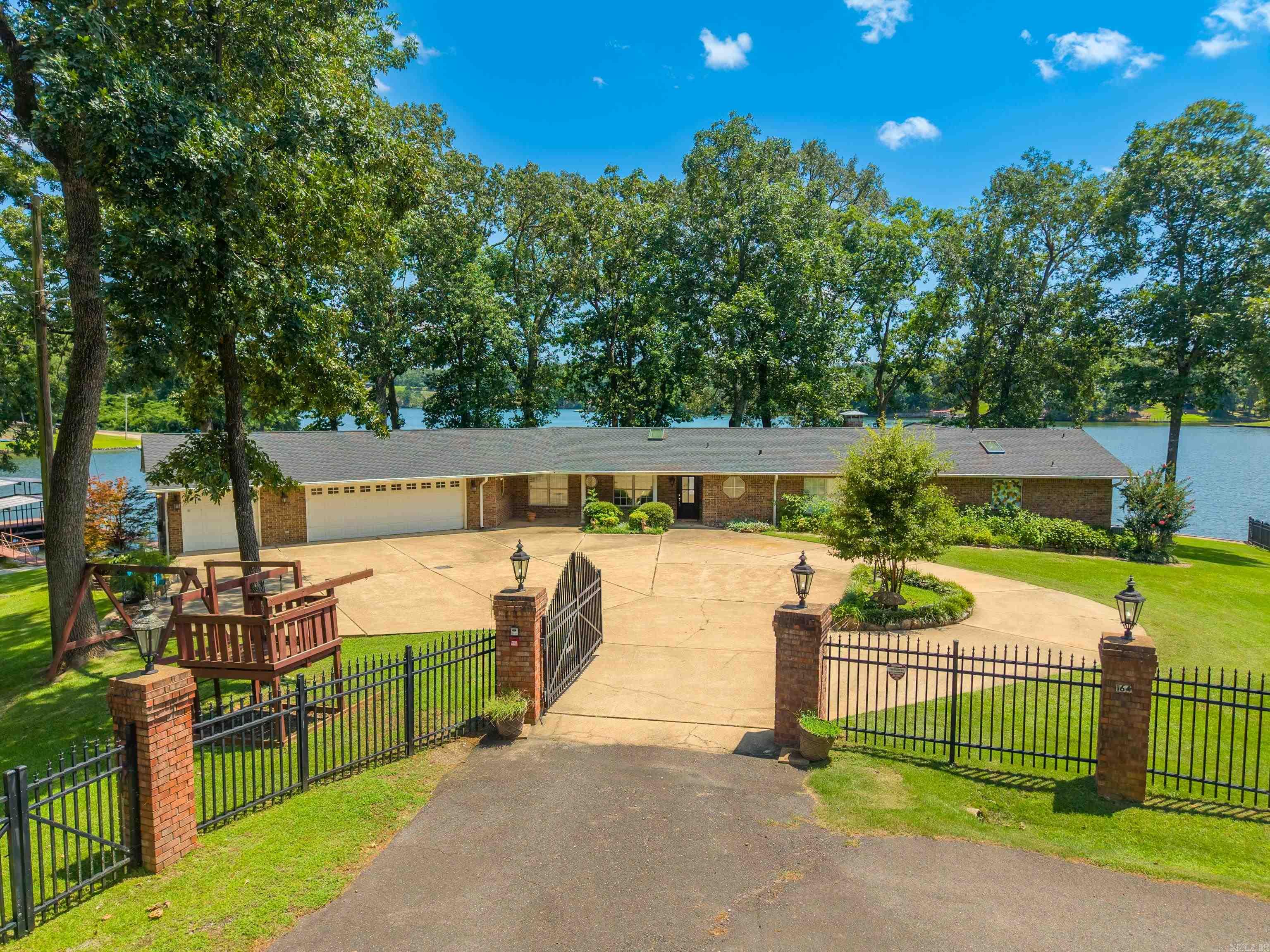 300+ ft of Waterfront on Lake Hamilton! Rare point lot, gated, near-level to water. 3 bed, 3 bath. Two-slip covered dock, 4-car garage, covered patio. New kitchen, new flooring, skylights throughout. Primary bath features a freestanding tub and stained-glass window. Words and Photos do not do this property justice! You need to see it in person. Schedule your showing today!