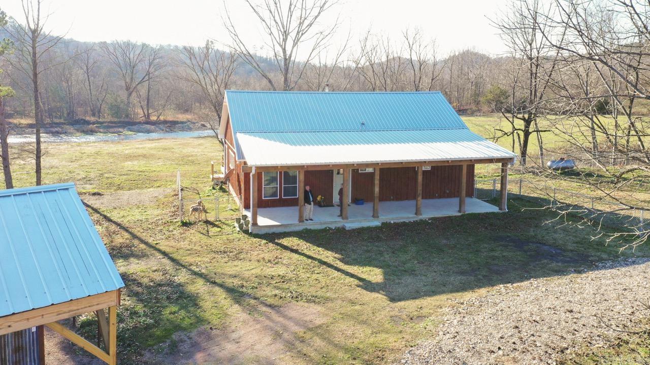 Situated on the banks of the beautiful, clear Caddo River, this unique property offers approximately 68.64 acres with land extending on both sides of the river, providing exceptional privacy and stunning natural surroundings. The home features an open floor plan designed for gathering and entertaining, highlighted by a large kitchen island with ample seating. Interior finishes include durable finished concrete flooring, a wood-burning stove, and an expansive wall of windows that frame breathtaking views of the river.  Additional living space includes a finished sunroom perfect for enjoying the scenery year-round. Outdoor features include two spacious decks and a fenced yard, creating ideal spaces for relaxing or hosting.  The property is well equipped for livestock, hobbies, or storage with a two-stall barn that includes a tack room, feed room, and workroom. The barn also features covered RV parking on a concrete slab, adding convenience for recreational or travel use.  With extensive river frontage, versatile acreage, and functional improvements, this rare property offers the perfect blend of country living, recreation, and privacy.