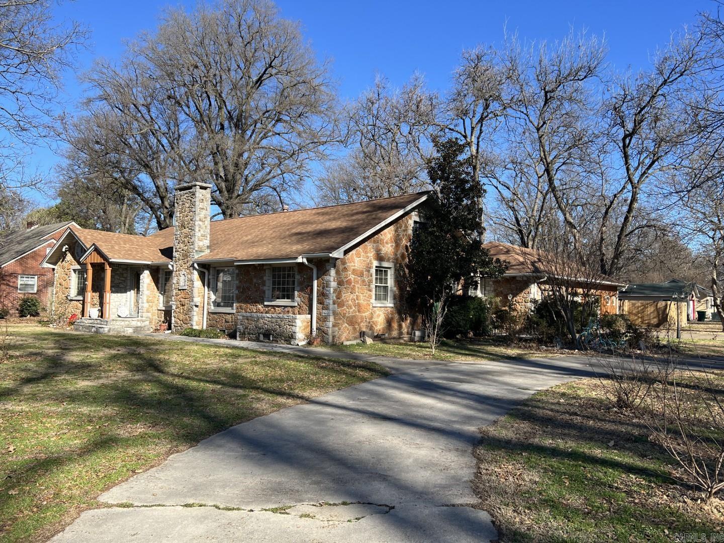 Located in Blytheville's Country Club Area, this vintage home is crafted from an unusual stone that gives it timeless character and curb appeal. The exterior is beautifully accented at the windows and the interior features some valuable updates. Inside, you’ll find a fireplace anchoring a spacious living room, three large bedrooms, and a kitchen remodel completed just five years ago. The current owner has also updated much of the plumbing under the home. New flooring was installed in the kitchen and primary suite but the lovely old hardwood still remains in much of the home. The primary bedroom is a large 18x14' and overlooks the backyard. The home sits well back from the road and includes a circular driveway off the side street, a side-entry two-car attached garage, an incorporated small shop, plus small backyard workshop. A truly unique property with character you don’t find every day.