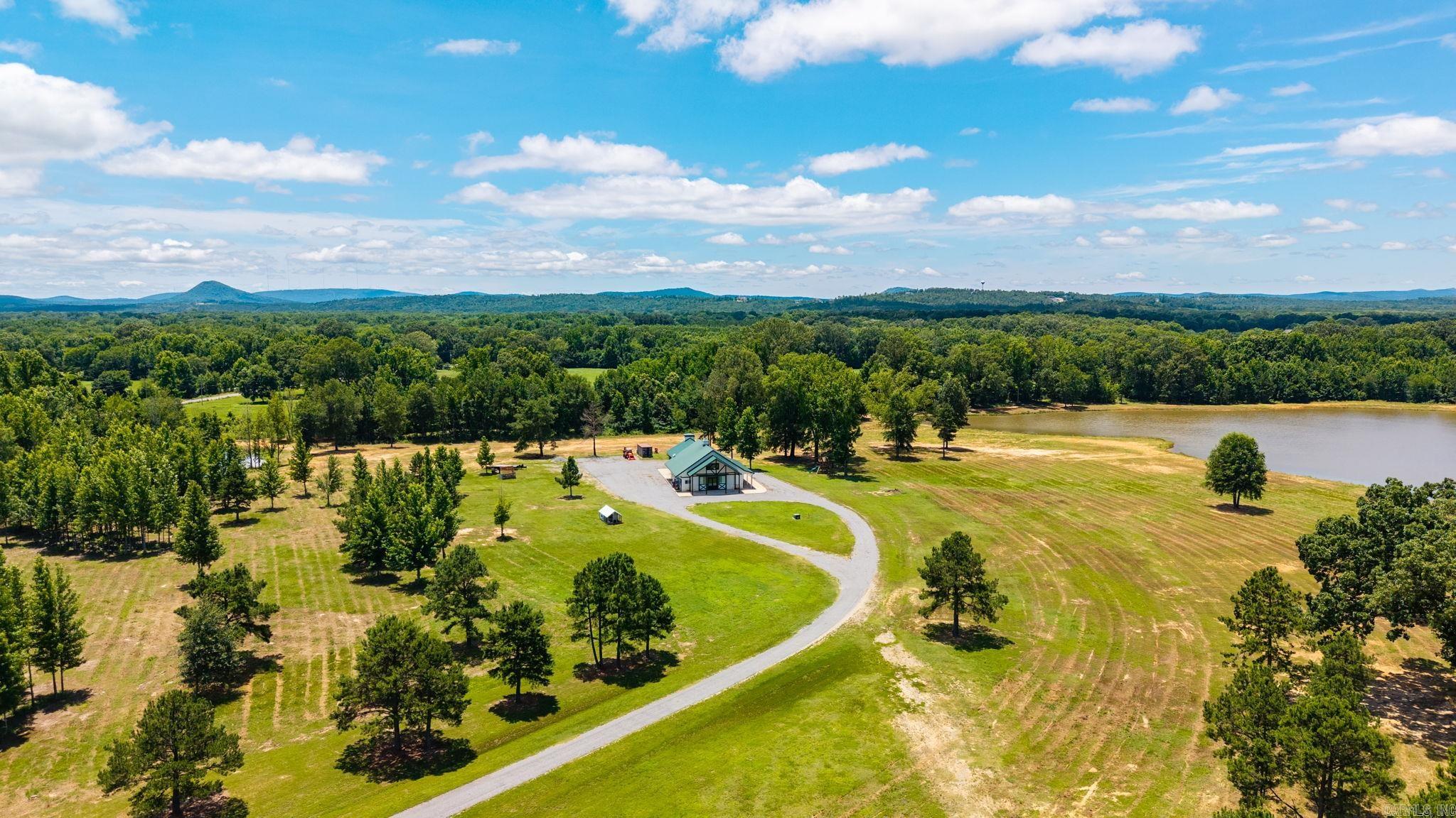 Private barndominium retreat on approximately 71 acres behind a gate featuring a mix of pasture, timber, and open land. Property includes a 26 acre pond and offers privacy, abundant wildlife, and plenty of space for recreation, livestock, or enjoying the surrounding countryside. There is also room to build an additional home if desired. The main living area features an open kitchen, dining, and living space with vaulted wood ceilings, abundant cabinetry, tons of counter space, and stainless appliances. Two bedrooms and a large bath with tiled wet room and soaker tub on the main level. A standout feature is the attached garage/recreation space with soaring wood ceilings, oversized glass garage doors, and flexible space for equipment, hobbies, or a full home gym. The area also includes a fireplace and seating area for indoor and outdoor gathering. Upstairs, the spacious primary suite offers a private retreat with sitting area, kitchenette, laundry, walk in closet, and bath with tiled shower. Windows overlook the acreage and surrounding countryside and is high fenced on three sides ($400k). This property has flexibility for residential, recreational, or agricultural use. Come see!