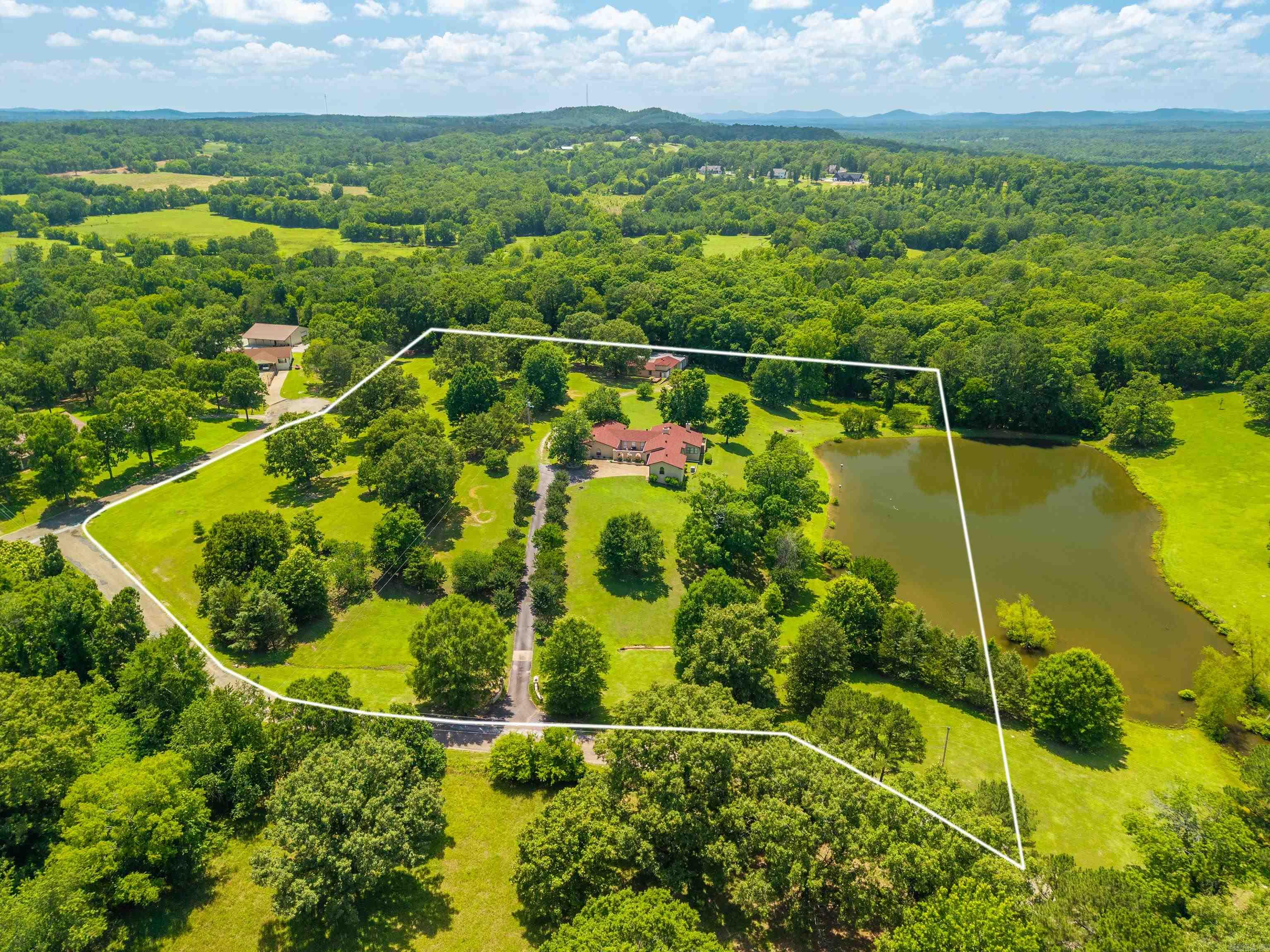 Welcome to your own private retreat in the highly sought-after Lake Hamilton School District! Nestled on 8.79 picturesque acres, this exceptional property offers the perfect blend of space, comfort, and functionality. Featuring four spacious bedrooms and four full bathrooms, this home is designed for both everyday living and entertaining. Inside, you’ll find three separate living areas, providing endless possibilities for gathering, relaxing, or creating the perfect game or media room. Plant enthusiasts will love the dedicated greenhouse, while the oversized laundry room adds everyday convenience. The primary suite is a true retreat, complete with two walk-in closets, separate his-and-her vanities, and plenty of space to unwind. Cozy up by one of the two wood-burning fireplaces or step outside to enjoy the hot tub overlooking your peaceful acreage. The beautiful pond adds to the serene setting, creating a true country oasis just minutes from town. Need space for hobbies, equipment, or a business? The impressive 4,000-square-foot workshop features five garage doors, ample workspace, and even includes its own sauna—a rare and incredible bonus.
