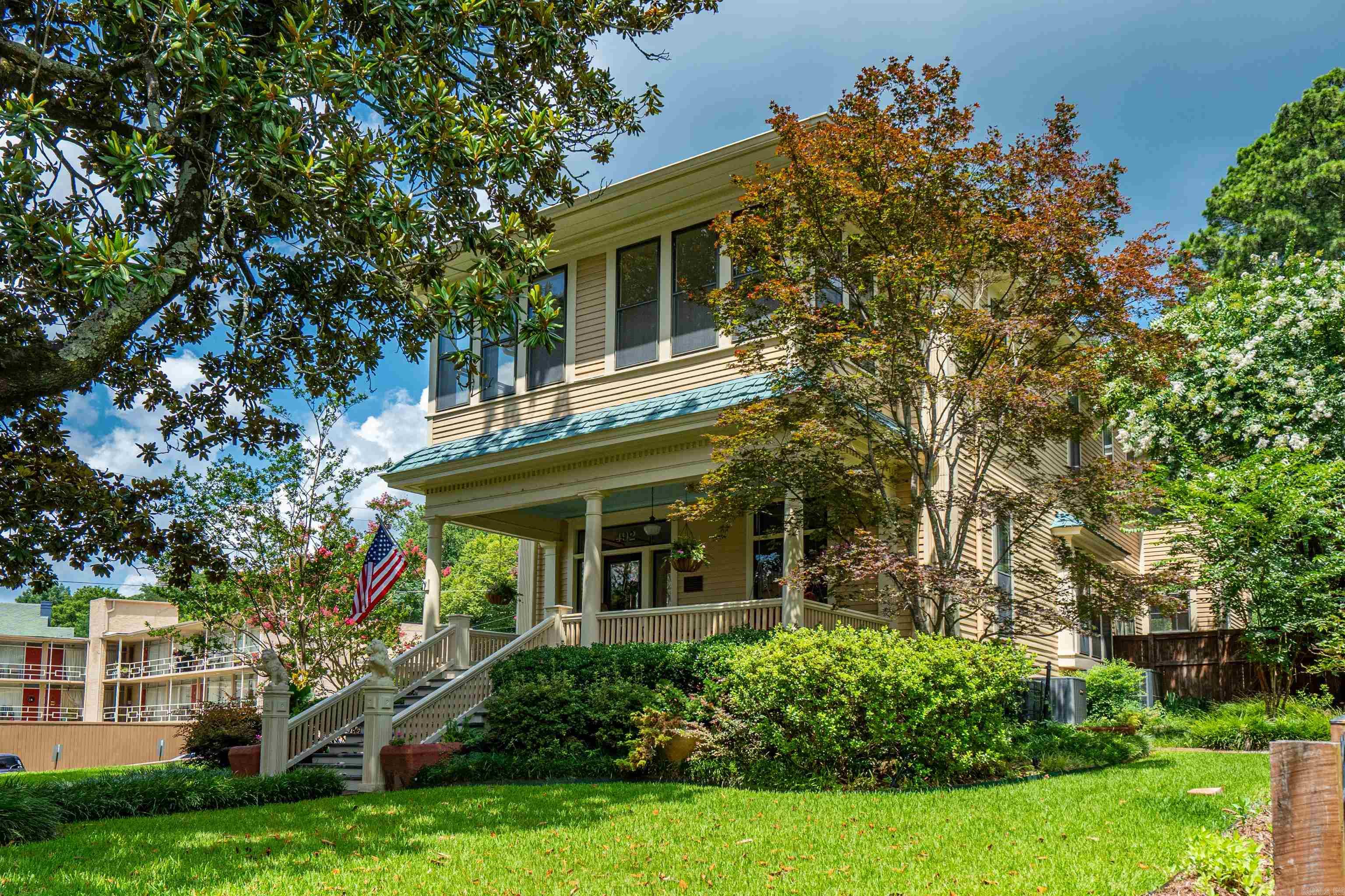 Some homes are simply houses. 492 Prospect Ave is a landmark, a Colonial Revival treasure in Hot Springs' Quapaw-Prospect neighborhood, officially recognized on the National Register of Historic Places by the U.S. Department of the Interior in 2002, joining a handful of area homes already individually recognized for their architectural significance. Developed between 1890 and 1950, this enclave of Quapaw and Prospect streets is prized for its exceptional mix of Colonial Revival, Craftsman, and Queen Anne architecture, and this, the Walter Beauchamp House, is one of its finest examples, blending architectural pedigree with modern comfort in equal measure. Stroll the brick walkway, framed by a low stone wall, with two mature magnolias, and thirteen blooming crepe myrtles, to a deep covered porch complete with a swing and rocking chairs, built for slow evenings and quiet mornings alike. The beautiful front door, with its own "492" address transom, opens into a grand foyer and entry hall, where a graceful staircase with turned balusters, a crystal chandelier, and gleaming grade "A" white oak floors set the tone for the whole home.