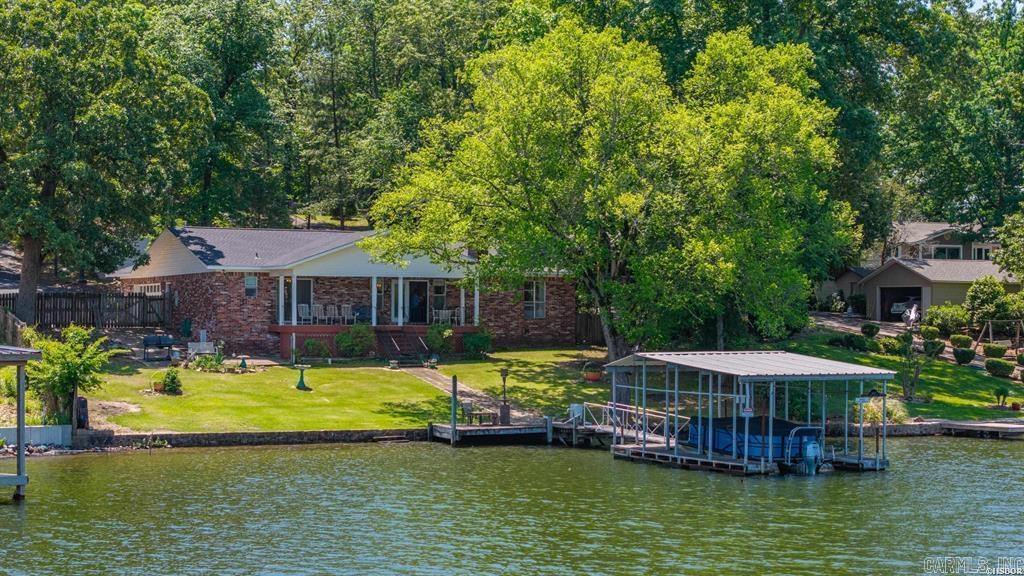 Beautiful waterfront home on Lake Hamilton offering stunning lake views and exceptional outdoor living! Privately positioned and not visible from the road, creating a true retreat-like feel. This 3-bedroom, 2-bath home features a large open living area with a cozy wood-burning fireplace, formal dining area, and breakfast nook perfect for everyday living and entertaining. The spacious primary suite includes an ensuite bath, breathtaking lake views, and private access to the backyard and covered sitting porch. Enjoy unbeatable views from the covered back porch overlooking the water. Continued..
