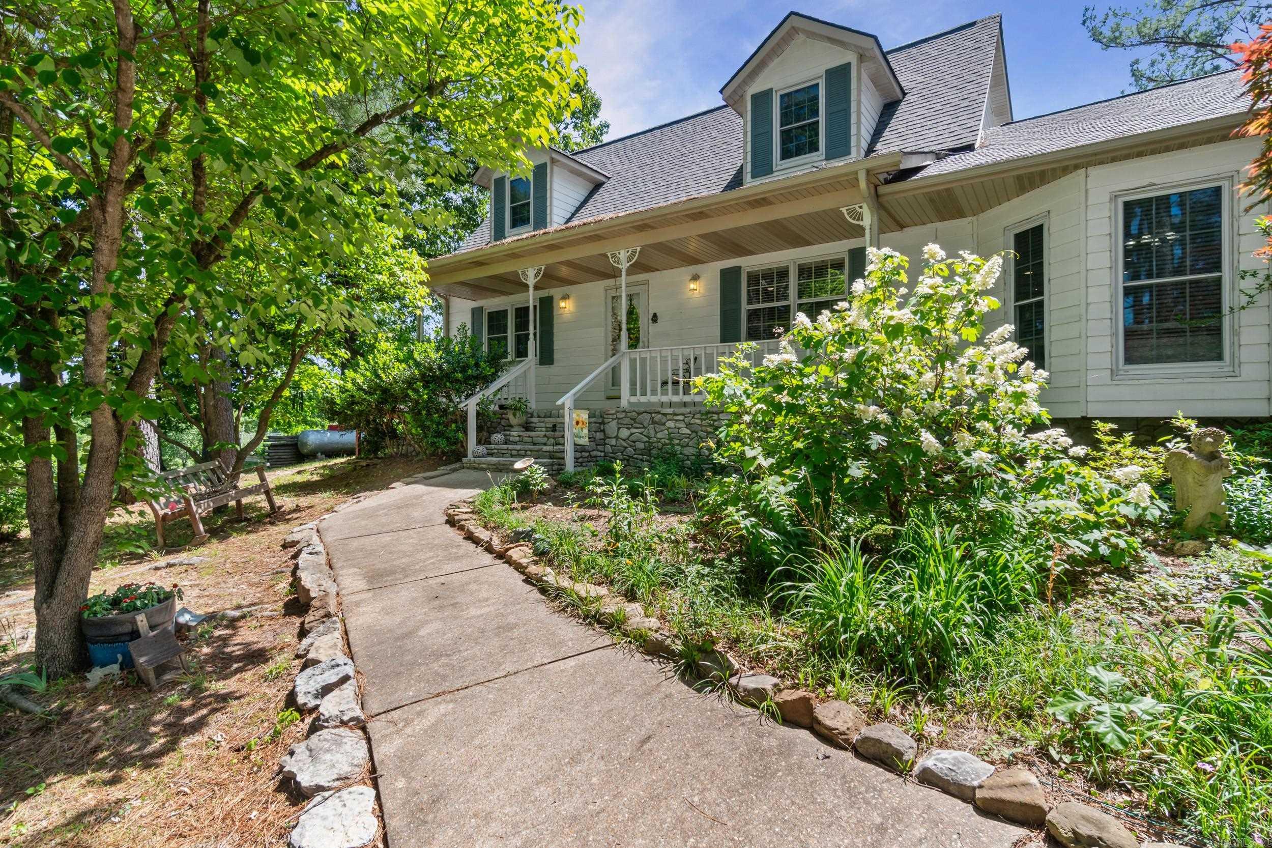 Beautifully designed home and garden estate on 2.2 lush acres in scenic Mountain View offering approx. 2,700 SF, 3 bedrooms, 3 full baths, and an attached 2-car garage. Ideally located just minutes from the Ozark Folk Center, downtown Mountain View, local music, dining, and only about 13 minutes from Round Bottom access on the White River—offering quick access to fishing, floating, and the best of Ozark recreation. Inside, the lower-level features updated flooring, a chef-style kitchen, breakfast room, spacious laundry/mud room nook with wash sink, updated bath with shower, private back entry, and a primary suite with large walk-in shower, jetted tub, and walk-in closet. Upstairs offers Tiffany-style lighting, additional bedrooms/bonus space, and a gorgeous glass-enclosed sunroom with private stairway leading to the back patio and gardens. Outdoors, enjoy wraparound decking, flowering gardens, muscadine vines, rolling hill views, and mature pines and hardwoods. Additional highlights include a heated and cooled art studio/office, covered RV parking with power and water, and a 24x30 barn with loft over a unique safe/storm room. An art lover’s paradise blending nature with luxury.