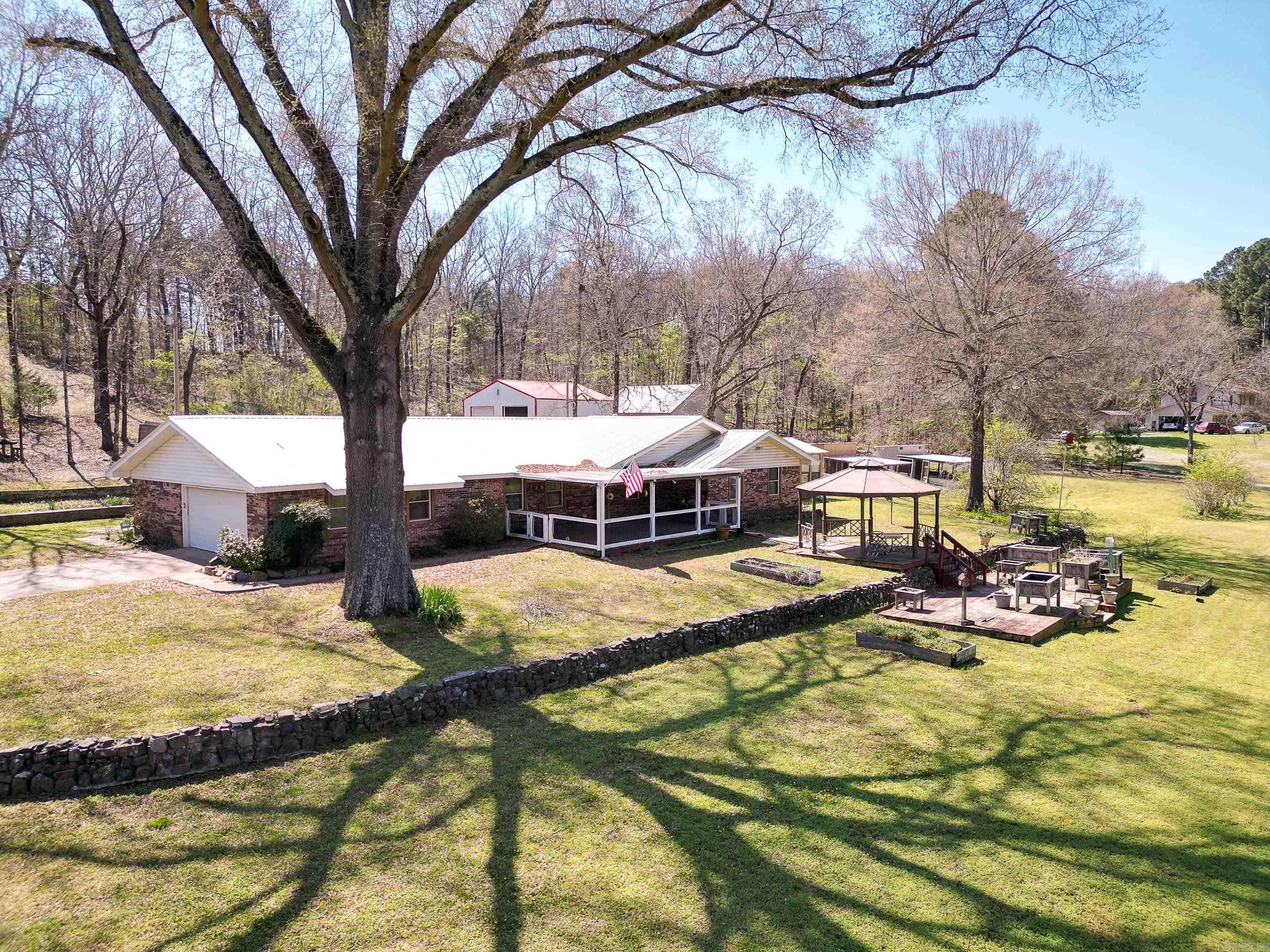 BACK ON MARKET (No fault of Owner) Discover the perfect blend of space, privacy, and potential with this 2,596 sq ft property nestled on 3.07 acres with exclusive (neighborhood) lake access and a private neighborhood boat dock. This versatile homestead features 4 bedrooms, 3 bathrooms, an office, bonus room, and a spacious layout ready for your personal touch. Outdoors, enjoy a deck, gazebo, three chicken coops, and a greenhouse equipped with propane lines—ideal for hobby farming or sustainable living. Two large cedar-lined barn/garages offer automatic doors, electricity, and full heating and cooling, perfect for storage, workshops, or business use, with a third for good measure.  With a well for irrigation or small livestock and just a few updates needed, this unique 1975-built property is a rare opportunity to create your dream retreat.  Great Bones with some updates this would be a spectacular home and with perfect mechanic work area.  Room for big toys.  Everything is running and operational, cosmetic improvements needed.  refrigerator, washer and dryer included.  Generator and compressor negotiable. If you have vision, you have a home.