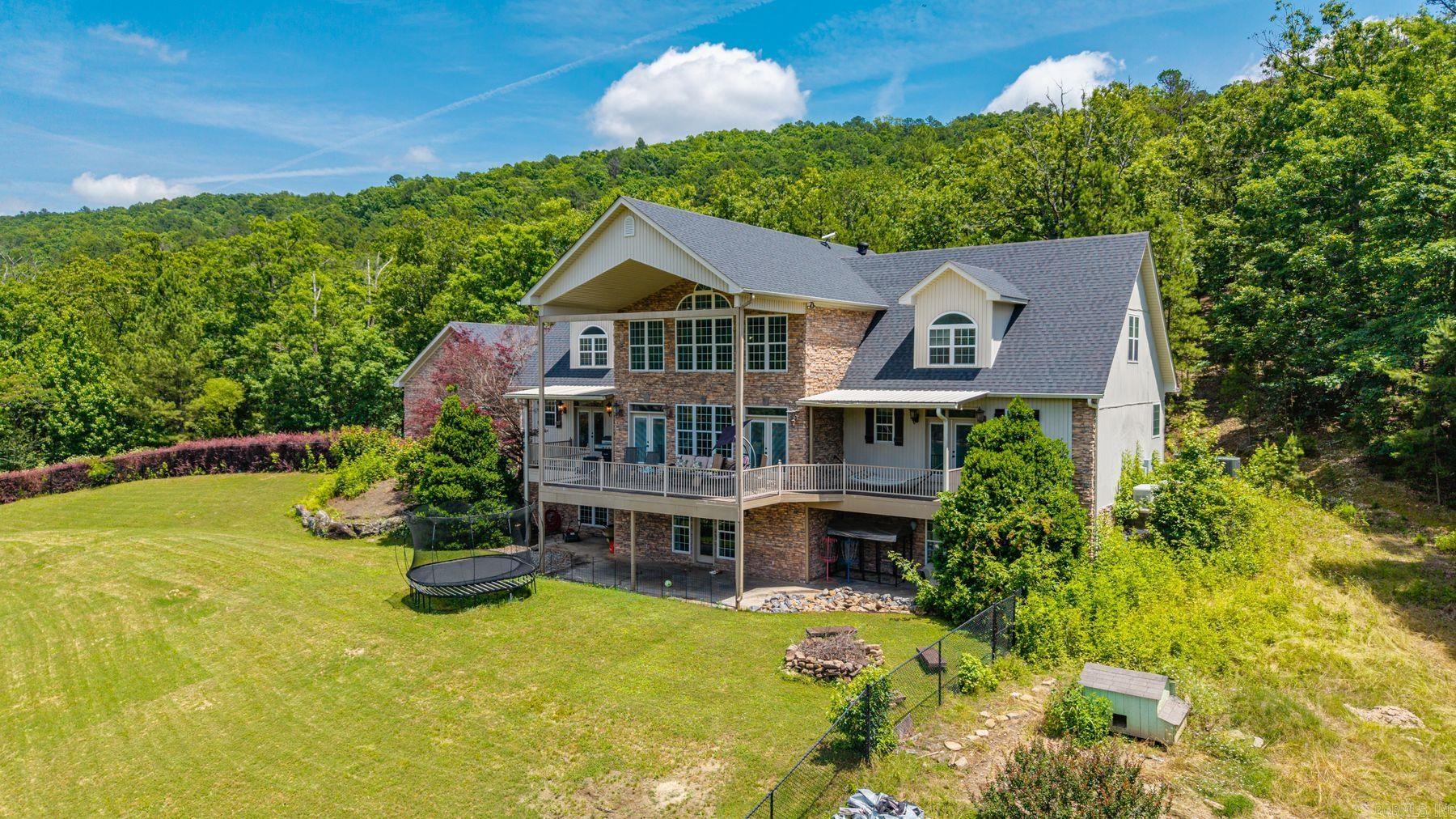 Experience elevated lakeside living at this stunning custom home on Peaceful Valley Rd., set on a private 40-acre bass lake shared by only four residences. Located just minutes from historic Hot Springs, this 5,232 sq ft property offers exceptional privacy, scenic water views, and a boat dock for direct lake access. The main level features a gourmet kitchen with marble countertops, large island with breakfast bar, and a spacious dining area ideal for gatherings. Oak hardwood and tile flooring enhance the living spaces. The primary suite includes 2 walk-in closets and a beautifully updated shower, with a second bedroom also on the main level. Upstairs offers an expansive loft plus 2 additional bedrooms and bathrooms. The fully furnished walk-out basement is designed for entertaining with a game room, full kitchen, theater room, and additional bedroom with bath. Additional features include a 3-car garage, 2 HVAC units, two Generac generators, new roof, and updated basement flooring. Enjoy a peaceful waterfront setting with excellent fishing and outdoor recreation right outside your door.