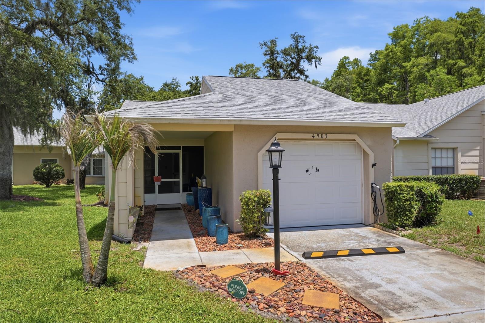 Virtually Staged. Welcome to carefree living in this 2-bedroom, 2-bath villa located in a desirable 55+ active adult community of Heritage Lake. This low-maintenance home features a 1-car garage and numerous recent upgrades for peace of mind and modern comfort. Enjoy a newer roof (2022), newer A/C system (2024), EV car charger, and gutters with leaf guards and a lifetime warranty. The home also has a new screened porch. The kitchen shines with brand-new appliances, while both bathrooms have been tastefully remodeled. The HOA has already scheduled exterior painting for July, adding even more value and curb appeal. Best of all, there are no assessments, and the HOA allows pets. Take a short stroll down tree-lined winding streets dotted with serene ponds to the vibrant community clubhouse. Residents enjoy an impressive array of amenities, including a heated pool and spa, tennis courts, pickleball, bocce, shuffleboard, billiards and card rooms, a library, exercise classes, and a full calendar of social activities. Whether you're looking to stay active, meet new friends, or simply relax, this community has something for everyone.  This home is in a highly sought-after Trinity location, with convenient access to shopping, dining, medical facilities, parks, golf, and everything the area has to offer. Move-in ready and waiting for you to enjoy the Florida lifestyle!