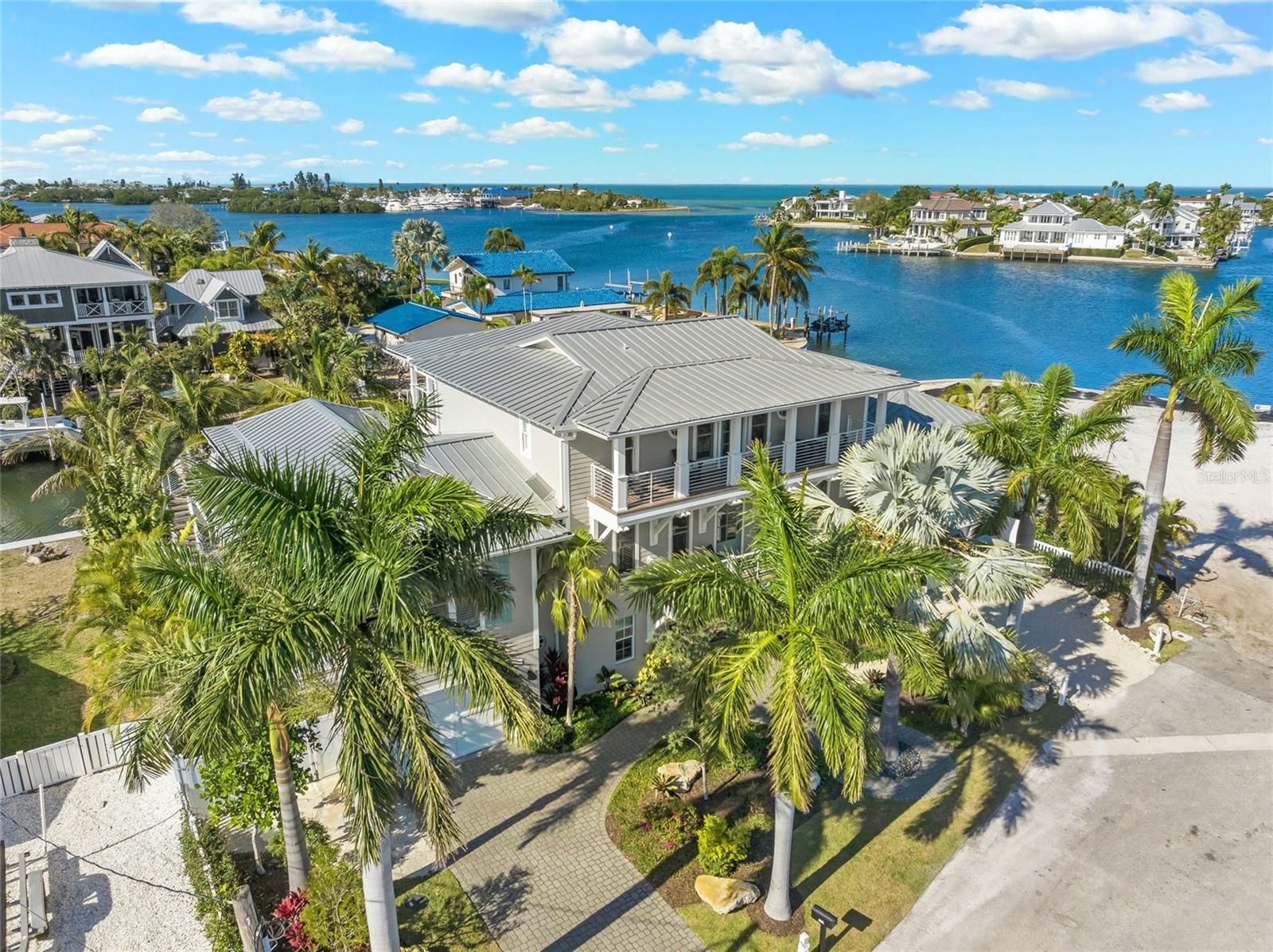 PRICE IMPROVEMENT! Some homes are just special.  They have an energy and flow that you feel the minute you walk inside and are surrounded by their tranquil beauty.  This stunning, Transitional Coastal Home with over 6,000 sq ft of indoor livable space, was completely remodeled by Gagne Construction in 2022. Every space has been thoughtfully  remade with intricate beamed ceilings, custom built-ins and sophisticated finishes, all in a serene color palette creating a stunning seaside retreat.  This prestigious home, with breathtaking views of Bimini Bay, is situated on a deep water canal offering quick access to open waters and the GULF OF MEXICO.  The interior design, meticulously crafted by Jessica Holmes Holiday, of HSH Designs, showcases a perfect blend of coastal charm and modern sophistication.  As you enter the home, a spacious foyer, leads to the ground floor game room offering over 2000 sq ft of bonus indoor living! Take the wide stair case or elevator to the main floor of the home,  and be greeted by a grand open space, seamlessly connecting living, dining, and kitchen areas all overlooking a massive balcony running the entire length of the room.  The gourmet kitchen is equipped with top-of-the-line Wolf and Subzero appliances, separate prep sink and ice maker, custom cabinetry, quartz counter tops, oversized island and unique designer lighting.  Every detail has been carefully chosen to create a space that is both functional and visually stunning.  The home features 4 well appointed and spacious bedrooms all with en-suites.  The primary bedroom is a true retreat, boasting a spacious layout, luxurious en-suite bathroom with radiant floor heating, a lavish custom walk in closet with a designated work space and a private balcony overlooking Bimini Bay.  The exterior of the home has a Key West influence with multiple covered balconies connecting every space to the outdoors, inviting you to relax and take in the view.  A salt water pool and spa, a separate hot springs hot tub, an outdoor kitchen area with retractable screens equipped with a EVO hibachi and large gas grill, putting green and outdoor shower are some of the included amenities.  The highlight of this waterfront retreat is having your boat in your back yard to explore the open waters, pull up on a nearby sandbar to swim and picnic, or stop off at one of the local restaurants to dine waterside.  The extensive dock includes a 10,000 lb boat lift, and a lowering platform and ramp for kayaks and paddle boards making it convenient to enjoy water activities and dolphin watching whenever you desire.  Some additional features are; Lutron lighting, security cameras, Ring Doorbell and locks, Audio system throughout, Tesla Charging Dock, 4 car garage,  included Gem Car, Hunter Douglas custom blinds, impact windows and doors and Zuri decking. Contact us today to schedule a private showing and experience the beauty and elegance of this one of a kind home for yourself!