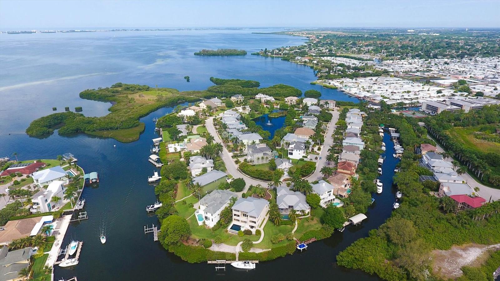 Discover the opportunity to own a distinctive residence in the gated waterfront community of Hawks Harbor, ideally between Sarasota and West Bradenton with convenient access to gorgeous Gulf beaches, IMG Academy, Sarasota-Bradenton International Airport, dining, shopping and cultural attractions. On an oversized 0.37-acre homesite with mature landscaping and privacy potential, this three-story home includes a deeded 26-foot boat slip in the Hawks Harbor marina with direct access to Sarasota Bay and no bridges to open water. Offering approximately 2,070 square feet of interior living space and 3,829 total square feet, the residence features three bedrooms and three full baths, with room for customization and expansion. Natural light fills the open-concept living area featuring volume ceilings, French doors to the wraparound terrace, hickory hardwood flooring and a renovated wood-burning fireplace. The kitchen includes granite countertops, a spacious center island, newer stainless steel appliances, a custom backsplash and a new sink. The recently renovated baths showcase Moroccan brass and intricate tile detailing and feature custom lighting (shower glass to be installed in primary bathroom, not pictured). The primary suite features two closets and an expansive loft-style flex space overlooking the living area, ideal for a dressing area, office or additional storage, while the second bedroom also includes a generous walk-in closet. Additional improvements include a 2023 metal roof, renovated deck, fresh interior paint, double-pane windows, irrigation system, central vacuum setup and two separate newer air-conditioning systems (2023 and 2021). The top level features a windowed cupola with an outdoor rooftop viewing deck ideal to survey the landscape of Hawks Harbor with a peekaboo view of the Bay. A designated space beneath the home offers potential for a future elevator installation. The oversized homesite allows room to expand the residence by 1,000+ square feet, add an outdoor pool and entertainment space, or construct an additional garage bay, subject to approvals. According to the seller, the property did not experience flooding during the 2024 storms. Additional features include a two-car under-building garage with storage space and generator pad. This residence represents one of the compelling entry points into Hawks Harbor, offering exceptional opportunity to personalize, expand and build long-term value with boating access in one of the Sarasota-Bradenton area’s ideally positioned gated waterfront communities.