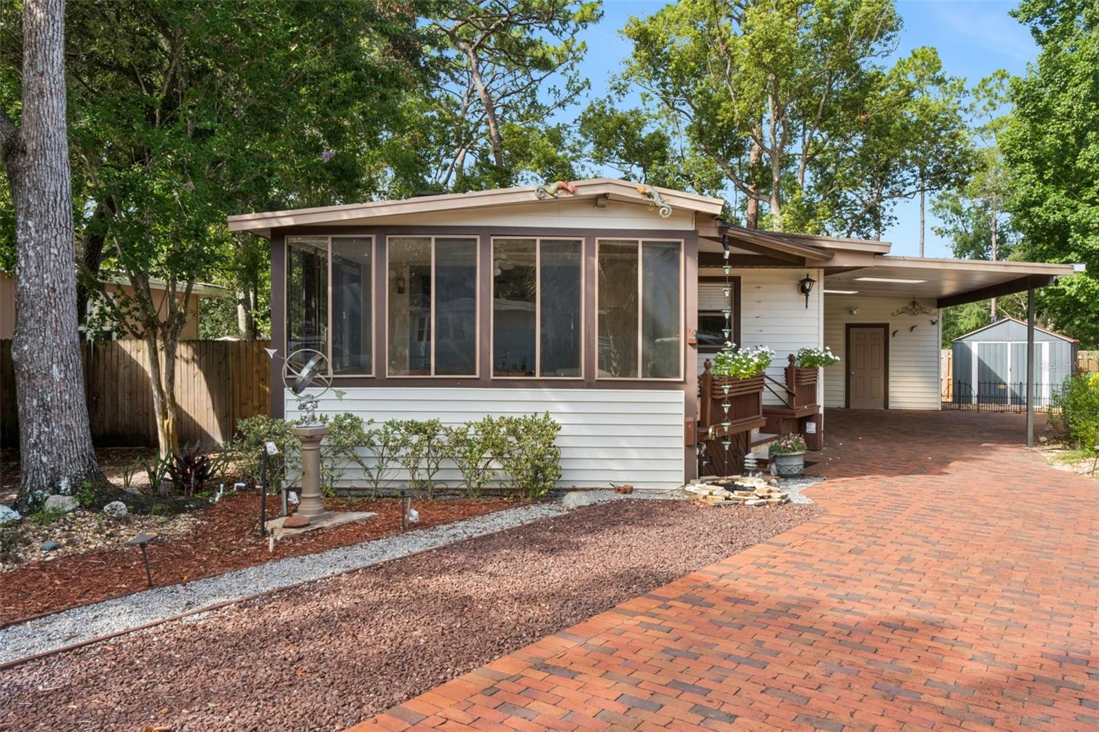 Welcome home to this charming and well-maintained 2-bedroom, 2-bath home tucked away on a quiet cul-de-sac in The Forest, one of Lake Mary’s most desirable gated 55+ communities. From the moment you arrive, you’ll appreciate the oversized brick paver driveway with an expansive covered parking area that easily accommodates multiple vehicles plus your golf cart.  Step inside to a bright and inviting Florida room with vaulted ceilings, creating the perfect space to relax, entertain, or simply enjoy the beautiful natural light. The Florida room flows seamlessly into the spacious living room, where you’ll find built-in shelving and a cozy electric fireplace that adds warmth and character.  
The separate kitchen offers an efficient layout with generous counter space and plenty of room for preparing meals. Just outside the kitchen is a wonderful wood deck—an ideal spot for morning coffee or evening gatherings. The deck wraps around the back of the home and is perfectly suited for future screening to create an additional outdoor living space.  The spacious primary suite features French doors opening directly onto the deck, a large walk-in closet, and a private bath. The fenced backyard provides privacy and room for pets or gardening, while a large detached storage/laundry room and an additional metal storage shed offer exceptional storage for tools, hobbies, and seasonal items.  Living in The Forest means enjoying an active resort-style lifestyle with outstanding amenities, including:

Gated 55+ community in the heart of Lake Mary
Two swimming pools, including a heated pool
Hot tub and men’s and women’s saunas
Tennis and pickleball courts
Shuffleboard courts
Beautiful clubhouse with stage, full kitchen, library, billiards room, card room, craft room, and meeting spaces
Walking trails and scenic green spaces
RV and boat storage available for a nominal fee
Cable, high-speed internet, and trash service included in the HOA
Active social calendar with dances, bingo, dinners, clubs, fitness activities, and year-round community events
Conveniently located just minutes from I-4, shopping, restaurants, medical facilities, Publix, Target, HomeGoods, TJ Maxx, and the Seminole Wekiva Trail, this home offers the perfect combination of comfort, convenience, and an exceptional Florida lifestyle. Whether you’re looking for a full-time residence or a seasonal retreat, this delightful home is ready to welcome you.
