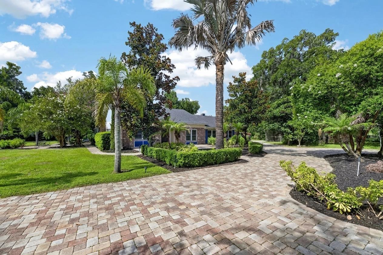 Virtually Staged. *5-BEDROOM ESTATE ON 1.5 ACRES WITH POOL, SPA, OVER-SIZED GARAGES, WORKSHOP & EXCEPTIONAL OUTDOOR LIVING* UPDATES INCLUDE - 2023: REPLACED ROOF, 5-TON A/C INSTALLED, EXTERIOR OF HOME AND GARAGES PAINTED, REPLACED SEPTIC SYSTEM, NEW CARPETING INSTALLED, AND NEW FRONT DOOR INSTALLED.  2024: ADDED WATER SOFTENER AND FILTRATION SYSTEM.  2025: REMODELED PRIMARY BATH SHOWER WITH NATURAL STONE, MODERNIZED IRRIGATION AND SPRINKLER SYSTEM, AND REPLACED HOT WATER HEATER. This stunning 5-bedroom, 2½-bath estate is a rare opportunity to own a beautifully maintained home on 1.5 private acres, offering the perfect combination of space, comfort, and outstanding amenities. From the moment you arrive, the impressive curb appeal makes a lasting impression with a circular paver driveway, lush landscaping, and an elegant front entrance.  Inside, you'll find more than 3,000 square feet of thoughtfully designed living space, all on one level. The open yet functional floor plan is ideal for both everyday living and entertaining, featuring rich wood cabinetry, granite countertops, plantation shutters, and a charming brick wood-burning fireplace that adds warmth and character throughout.  The spacious kitchen serves as the heart of the home, offering abundant storage with double pantries, custom roll-out shelving, extensive counter space, and a large center island perfect for meal preparation, casual dining, and gathering with family and friends. The kitchen flows seamlessly into the inviting family room, the Florida room overlooking the pool, and an oversized dining room designed to accommodate large gatherings, holiday celebrations, and special occasions.  A desirable tri-split bedroom floor plan provides privacy and flexibility for family members and guests. All five bedrooms are generously sized and feature custom closet built-ins. The oversized laundry room offers exceptional functionality with a utility sink, extensive storage, and space for an additional refrigerator. Step outside and discover your own private backyard retreat. The screened pool and heated spa are complemented by a covered lanai, additional patio space, and a winding walkway leading to a dedicated fire pit area—perfect for relaxing evenings or entertaining guests year-round.  Adding even more value and versatility, the property features two detached garages with room for up to six vehicles. The larger garage includes water, air conditioning, electricity, and sewer connections, making it ideal as a workshop, home business, RV storage, or boat storage. Additional outbuildings include a storage shed and a chicken coop. For those who work remotely or travel frequently, this property offers the best of both worlds: peaceful country living with high-speed internet and convenient access to major destinations, including a drive of approximately 40 minutes to Tampa International Airport. Offering an exceptional blend of comfort, functionality, privacy, and outdoor living, this unique property is ready to welcome its next owners. Thank you for your interest and for taking the time to see this home in person.
