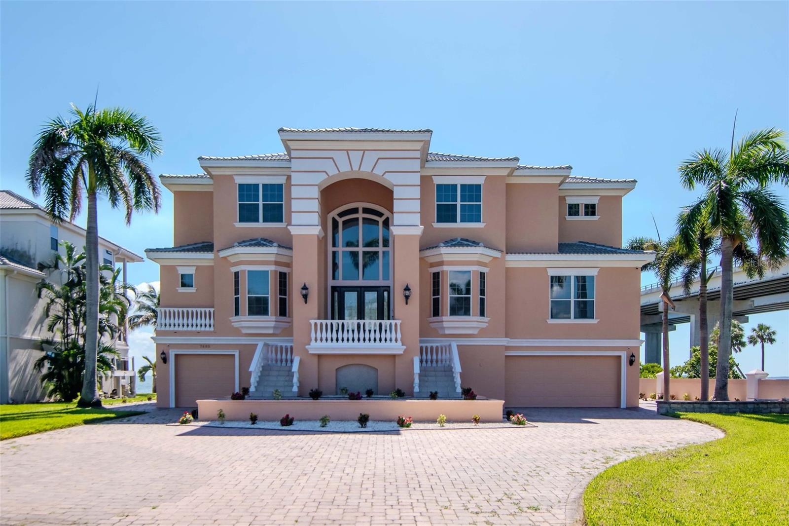 Virtually Staged. Experience the best of waterfront living in this beautifully appointed 5-bedroom, 6-bath residence offering 4,168 square feet of thoughtfully designed space. Built in 2000, this elegant home is perfectly positioned to showcase sweeping views of Tampa Bay and the iconic Sunshine Skyway Bridge.
Ideal for the car enthusiast, the entire first level serves as an expansive garage that can easily accommodate a sizable collection. With two full bathrooms for poolside convenience and a generous flex space currently used as a bar, the lower level offers versatility for entertaining or additional storage.
Upon entering the foyer, you are greeted by a dramatic two-story living room where oversized windows bathe the space in natural light and frame unobstructed views of the bay. The open, split-floorplan centers around the primary suite, a serene retreat featuring dual walk-in closets, a spacious bath with soaking tub and walk-in shower, and private access—via a spiral staircase—to the dedicated upstairs office or study.
Designed for entertaining, the expansive kitchen offers abundant counter space for meal prep, a breakfast nook overlooking the water, and seamless flow to the living and dining areas. Guests will appreciate the convenience of a downstairs bedroom located near an adjacent full bath—perfect for comfort and accessibility.
The third floor hosts three additional bedrooms, including one ensuite and two connected by a Jack-and-Jill bath. The office/study and rear bedroom each open to their own terraces, providing idyllic spaces to enjoy daily sunrises, sunsets, and the tranquil beauty of the bay.
Located within an exclusive gated cul-de-sac of just seven luxury homes, this property offers privacy, security, and an elevated sense of retreat. Boating enthusiasts will love the private dock equipped with a lift and jet ski floating dock—perfect for effortless days on the water and prime fishing for the sportsman.
A rare opportunity to own a waterfront sanctuary that seamlessly blends luxury, comfort, and the unmatched allure of Tampa Bay living.