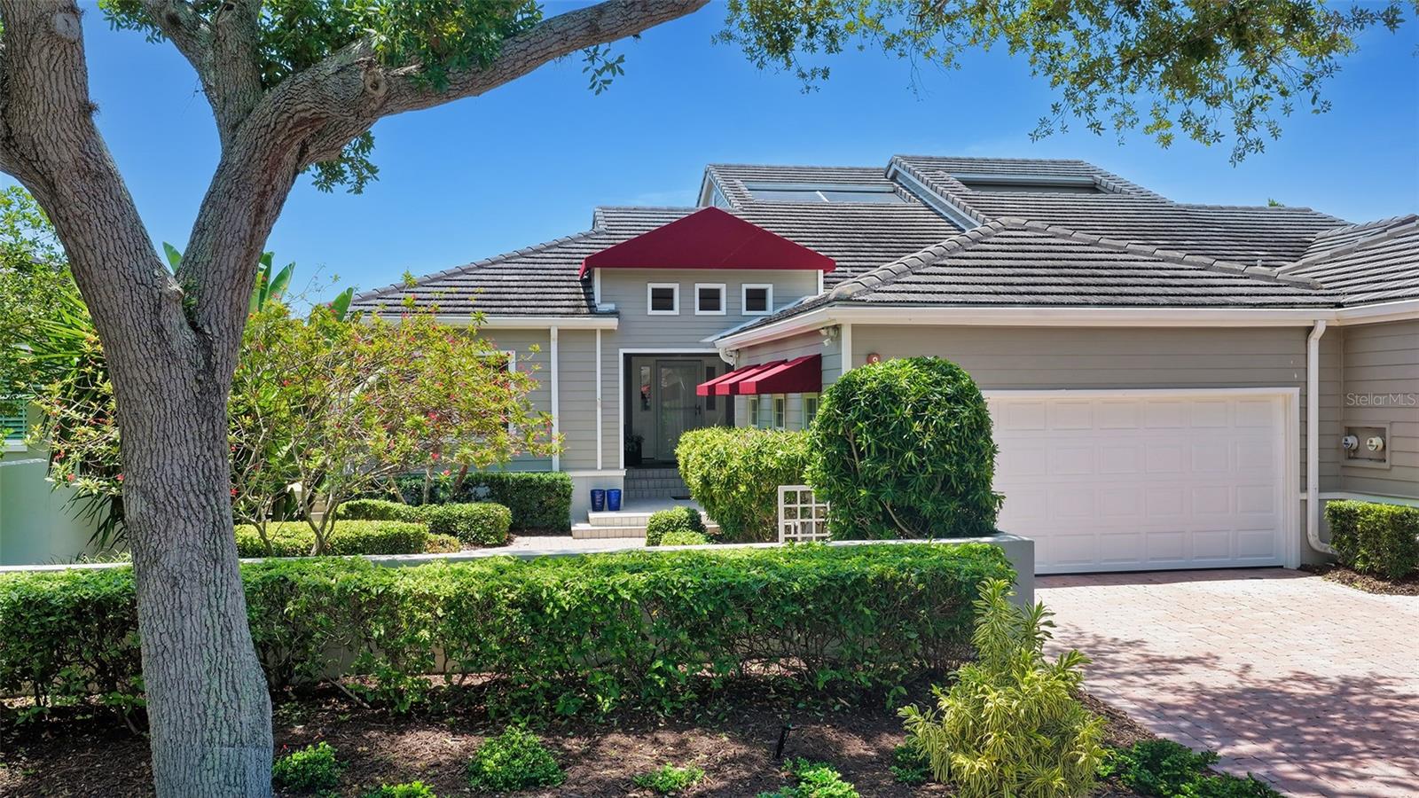 Tucked within Winding Oaks, one of Longboat Key’s most sought-after villa communities, this 3BR/3BA residence offers the scale and comfort of a single-family home paired with the simplicity of maintenance-free living. From the paver drive and walkway to the stepped front entry, the residence creates an inviting first impression before opening into a home defined by volume, light and connection to the outdoors. Step inside and soaring ceilings immediately create a sense of openness, while high-set windows invite natural light to move throughout the living spaces. Tile flooring and soft neutral tones create a clean backdrop that complements the peaceful setting just beyond the glass. Renovated in November 2025, the kitchen has been thoughtfully opened and redesigned into a true centerpiece for gathering and everyday living. A substantial island with seating anchors the space, along with stone countertops, white cabinetry, stainless steel appliances, a range hood, wine refrigerator and tile backsplash. An abundance of windows and an adjoining sitting area create a bright, welcoming space whether hosting guests or enjoying a quiet morning. The dining area transitions naturally into the living room, where cathedral ceilings, a corner fireplace and sliding glass doors connect the interior to the outdoors. Beyond, an expansive screened deck overlooks the community lake and fountain, creating a peaceful setting with multiple areas for dining, relaxing or entertaining. Privacy walls on either side enhance the feeling of seclusion while keeping the water views front and center. The primary suite is spacious and calming, featuring vaulted ceilings, engineered wood floors, a wall of sliding glass doors opening to the deck and a large walk-in closet with extensive built-ins. Also renovated in November 2025, the primary bath offers dual vanities, a walk-in shower, dressing area and separate water closet. Guest accommodations are equally well planned. One bedroom includes an en suite bath and walk-in closet, while another is currently configured as an office space with sliding glass doors opening to a private patio. Updated baths throughout, an in-residence laundry room and a 2-car garage add convenience. Set within the Harbourside golf course community, Winding Oaks offers a serene environment with a gated entrance, community pool and spa, and access to the full range of Bay Isles amenities, including deeded beach access through the private Bay Isles Beach Club.