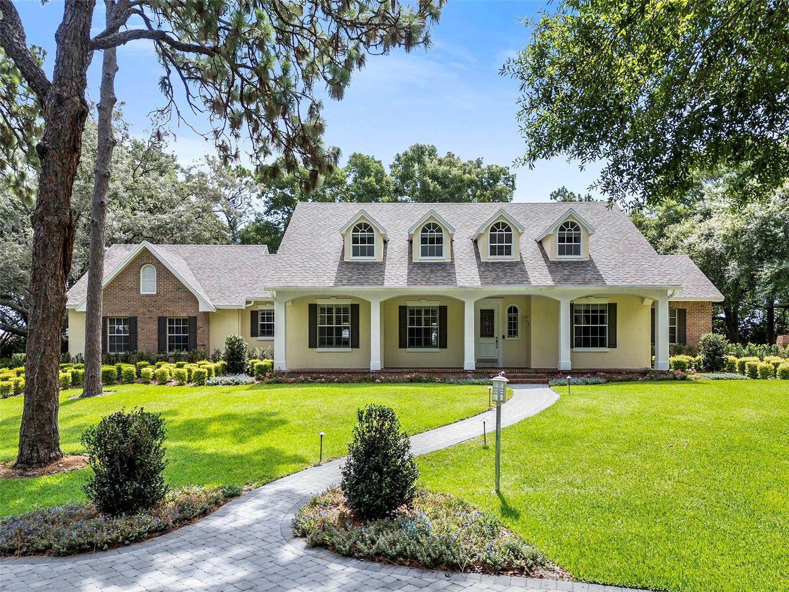 One or more photo(s) has been virtually staged. Offered for the first time in 25 years, this exceptional Southern Traditional estate presents a rare opportunity to own one of Longwood's most distinguished residences. Originally designed as the builder’s personal model home, this home showcases timeless craftsmanship, architectural charm, and meticulous pride of ownership throughout. Nestled on a professionally landscaped 1.01-acre homesite within the coveted Ravensbrook community, an intimate enclave of nearly 80 custom homes, treasured for its spacious lots and tree-lined streets shaded by a mature canopy of oaks. Impressive curb appeal sets the tone from the moment of arrival. A welcoming front porch, framed by lush mature landscaping, creates a an elegant first impression. Encompassing 3,443 square feet of thoughtfully designed living space, the home features 5-bedrooms, 4.5 bathrooms, and a highly desirable floor plan with both the primary suite and an additional bedroom located on the main level. A dramatic two-story entry welcomes guests with soaring 20-foot vaulted ceilings, marble tile floor, refined crown molding, Colonial trim details, raised-panel doors, plantation shutters, and exquisite beveled-glass transoms adorning every downstairs doorway. Designed for both everyday comfort and gracious entertaining, the heart of the home is highlighted by a stunning double-sided wood-burning fireplace, showcasing exceptional brick craftsmanship and engineered hardwood flooring. The kitchen boasts distinctive tongue-and-groove oak ceiling, granite countertops, a center island, stainless steel appliances, and a dining area for casual meals and gathering. Traditional swinging doors provide convenience to the separate formal dining room, creating an ideal flow for hosting dinners. The private primary suite serves as a luxurious retreat, complete with a beautifully renovated spa-inspired bathroom. Upstairs, 3 generously sized bedrooms, each enhanced by character-rich vaulted ceilings. One bedroom includes its own private ensuite bath and spacious walk-in closet. Completing the second floor is a separate bonus room located above the garage, featuring rich wood parquet flooring and a closet, offering flexibility as a media room, home office, fitness studio, playroom, or guest suite. French doors lead to a screened lanai overlooking the sparkling swimming pool and spa, complemented by a summer kitchen for storage and entertainment. Additional highlights include a well-appointed laundry room with built-in cabinetry, utility sink, washer and dryer, a three-car garage with epoxy-finished flooring and custom storage cabinets, and an expansive paver driveway that creates a grand arrival experience. For nature lovers and outdoor enthusiasts, Ravensbrook offers a unique lifestyle amenity through exclusive access to Cushman Park, a community waterfront lot named in honor of the original developer. Residents may enjoy Rice Lake for kayaking, paddleboarding, and other recreational pursuits. Ideally situated along the prestigious Markham Woods Corridor, residents enjoy convenient access to an array of shopping, dining, premier golf courses, and nature trails, all while zoned for Seminole County's highly sought-after public schools. Just minutes away is the renowned Seminole Wekiva Trail, a nearly 14-mile paved recreational trail, for walking, running, cycling, and enjoying Central Florida's natural beauty.