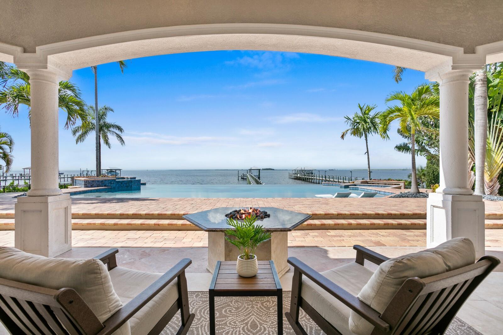Exquisite Waterfront Estate – Meticulously Remodeled & Reimagined. Nestled in the exclusive gated enclave of Mustique Bay, this magnificently remodeled waterfront estate offers an unparalleled blend of luxury, sophistication, and modern enhancements. Boasting exceptional living and entertaining areas indoors and out, with breathtaking views at every turn. Set on an expansive 100-foot-wide, .66-acre open Bay lot, this home has been transformed with extensive updates that elevate its elegance and functionality, making it one of the most remarkable residences on Tampa Bay. A gated entry and palm-lined drive welcomes you to a home that lives primarily as a single level, featuring new wood flooring throughout, modern lighting, and refined finishes. The gracious entryway leads to expansive living and dining areas with soaring ceilings and walls of glass that frame breathtaking waterfront views. A new stone feature wall with a fireplace creates a stunning focal point in the family room, adding warmth and architectural interest. The Chef’s kitchen has been completely redesigned, now showcasing Taj Mahal quartzite countertops, SubZero and Wolf appliances, a new wine refrigerator, custom cabinetry, and a spacious center island—all blending seamlessly into the open-concept living space. The grand FIRST-FLOOR master suite offers a tranquil retreat with spectacular Bay views, a double tray ceiling, and an opulent spa-inspired bath featuring a deep soaking tub, an expansive shower, and custom-designed finishes. Additional living spaces include a formal dining room, den/office (optional bedroom) and two additional first-floor guest suites with en-suite baths. Upstairs, a bonus/game room features a gracious waterfront terrace, along with an additional guest en-suite, half-bath and a fully rebuilt balcony with new tile and railings for a private guest haven and recreation. The outdoor living experience is truly resort-worthy. The saltwater infinity pool has been remodeled, featuring a new infinity edge, stunning new tile work, and a gas/electric hybrid pool heater. The covered outdoor living area now boasts a stone feature wall with a fireplace, along with a completely updated summer kitchen and built-in grill. A fire pit and multiple seating areas provide the perfect setting for waterfront gatherings, while a generous private dock, complete with a covered lift, new 20k boat lift motor and paver walkway provide direct access to Tampa Bay’s premier boating lifestyle. Additional top-tier upgrades include three new A/C units with updated ductwork, water softener and reverse osmosis system, landscape lighting and exterior fans, garage door system and gate controller, and upgraded window treatments. This spectacularly reimagined estate represents the pinnacle of waterfront luxury and modern elegance. Capture this extraordinary opportunity to own one of Tampa Bay’s most exclusive and meticulously remodeled properties and embrace all that Apollo Beach has to offer. This popular waterfront community delivers an abundance of recreation on and off the water with its central location and easy access to beaches, shopping, dining, parks, Tampa, St. Petersburg and Sarasota. Please view Virtual Tour for full Property Video and Floor Plan. BRAND NEW ROOF INSTALED JUNE 2025.