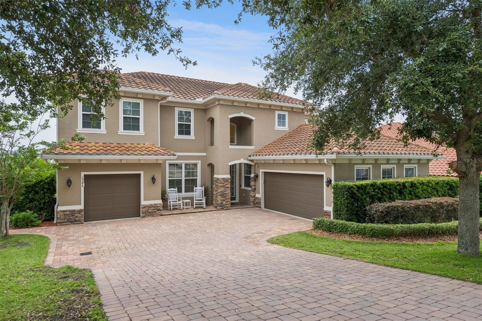 This 5-bedroom POOL HOME offers a rare blend of privacy and sophistication, situated on a PREMIUM LOT WITH NO REAR NEIGHBORS and sweeping, elevated views of Lake Felter. Nestled within the GATED COMMUNITY of Bella Lago, this executive home is centrally located in the heart of a vibrant lifestyle hub—surrounded by CHAMPIONSHIP GOLF COURSES and just minutes from local shops, gourmet restaurants, and craft breweries. The interior is defined by high-end finishes, including ENGINEERED WOOD FLOORING throughout the living areas and bedrooms, and elegant glass-panel French doors leading to the DOWNSTAIRS OFFICE and GUEST BEDROOM. At the heart of the home, the OPEN KITCHEN features a 5-burner gas cooktop with a VENTED STAINLESS STEEL HOOD, built-in DOUBLE OVENS, LARGE SINGLE BASIN SINK and crisp QUARTZ COUNTERTOPS accentuated by decorative tile and designer pendant lighting. Hosting is made effortless with a BUILT IN BUTLERS PANTRY on the main level and a dedicated DRY BAR with a BEVERAGE FRIDGE in the upstairs loft, where an electric fireplace adds a warm glow to the SECONDARY LIVING SPACE. The primary retreat serves as a true sanctuary, entered through private French doors and featuring its own electric fireplace, a CUSTOM ORGANIZED CLOSET, and a spa-like bath with a SEAMLESS GLASS SHOWER and garden tub. Modern convenience is integrated throughout, from the dedicated TECHNOLOGY CLOSET with DEDICATED HARD WIRED WiFi to the laundry room’s utility sink and additional cabinetry. Outside, the tropical oasis beckons with an EXPANSIVE PAVER DECK, a pool with a SUNSHELF, and an oversized 8-person spa, all complemented by a custom pergola and firepit area perfect for relaxing in the evenings. With a brand-new A/C (April 2025) and full gutters, every detail of this home has been meticulously curated for comfort and peace of mind.