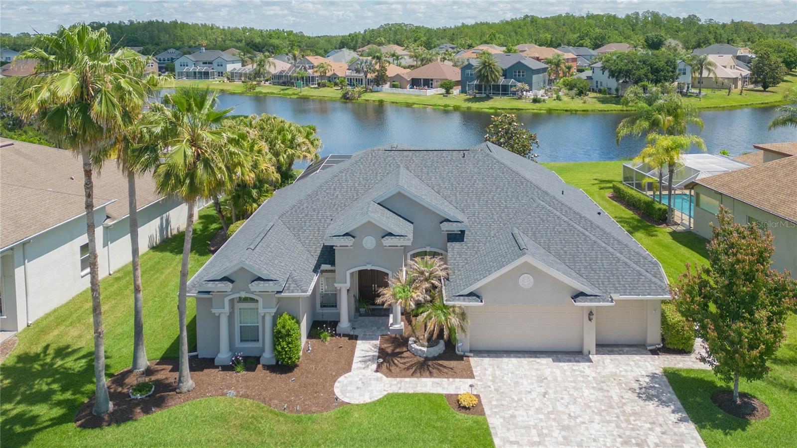 Stunning waterfront pool home located in the exclusive gated enclave of Fairgate in Seven Oaks, offering a quiet cul-de-sac setting with limited residences. Situated on a wide pond-front lot, the home offers 3,500+ sq ft of living space. A striking architectural presence, manicured landscaping, lighting, and paved driveway create a grand first impression. Soaring 10-foot ceilings and open light-filled floor plan sets the tone for elegant living. Featuring 4 bedrooms, 4 full baths, private office, formal living & dining rooms, expansive family room, and includes surround sound in-ceiling speakers, and a 3-car garage. The chef’s kitchen is beautifully reimagined with quartz counters, double sink, oversized island, cook-top, appliances, hidden walk-in pantry, & breakfast nook. A tranquil sunroom/library overlooks the pond, & spacious upstairs bonus room provides flexible space. Primary suite has serene water views, walk-in closets, & large bath with soaking tub, frameless glass shower, dual vanities.
Upgrades include engineered hardwood floors in all bedrooms & office, marble counters in all bathrooms with designer finishes (2020), new roof & gutters (2023), pool pump (2021), lanai pavers (2021), paved driveway (2025), water heater (2023), & water softener (2019). Replaced and adjusted all lawn sprinkler heads (2026), & security system. Seamless transition from indoor to outdoor living is experienced via sliding glass doors opening out to the breathtaking screened lanai, showcasing a sparkling pool, with uninterrupted panoramic views of the tranquil pond. Seven Oaks offers mature landscaping, winding trails, cycling paths, resort style club house, junior Olympic lap pool, water park/splash park, fitness center, movie theater, café, soccer, basketball, pickleball, & 5 tennis courts. Top-rated schools, minutes to I-75, with easy access to downtown Tampa, its International Airport, and near top rated hospitals, shopping, a variety of restaurants, golf courses and more.