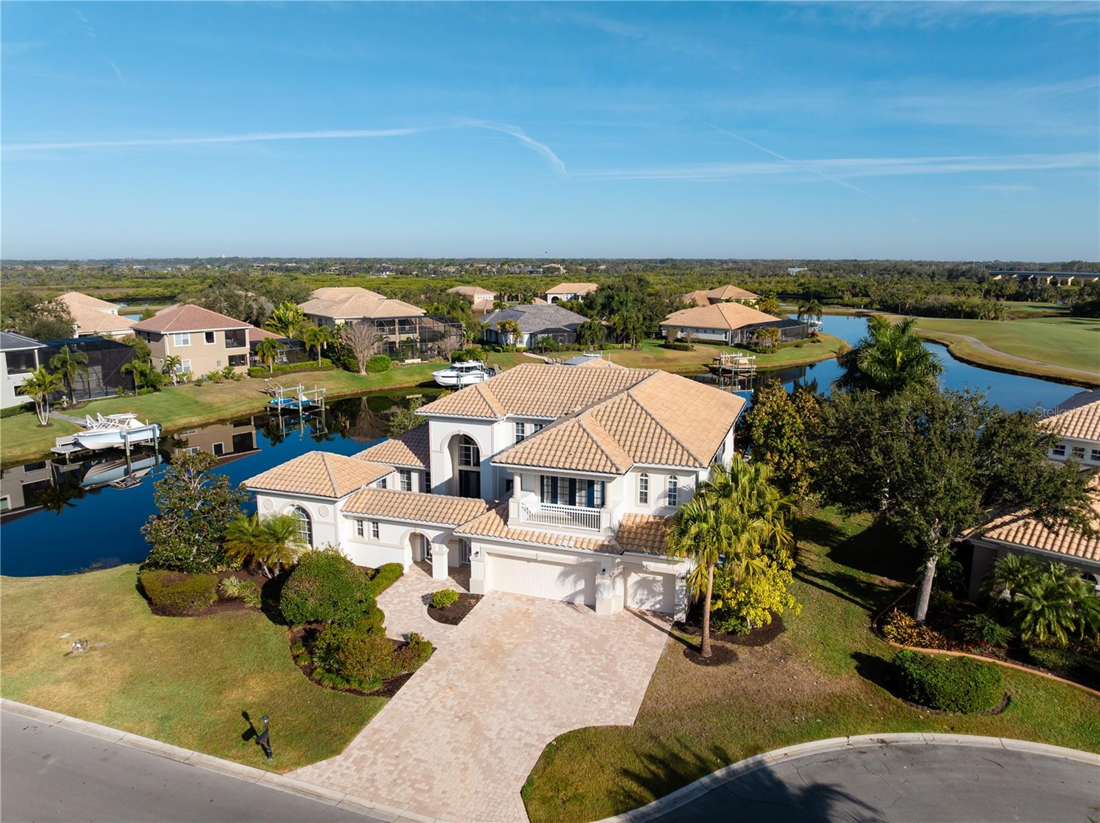 Stunning water and golf course views define this exceptional estate in the prestigious Waterlefe Golf & River Club, where refined luxury meets resort-style living. Designed for grand entertaining and everyday comfort, this expansive residence offers six bedrooms, five and a half baths, two primary suites located on both the main and upper levels, a private gated courtyard entry, and a separate one-bedroom casita with full bath, ideal for guests or multigenerational living. The interior showcases soaring vaulted ceilings, an impressive circular staircase, custom ceiling beams and accent wall features, luxury LVP flooring throughout, a dedicated movie theater and game room, and a chef’s kitchen featuring quartz countertops, a double waterfall island, Fisher & Paykel appliances, a 40-inch gas range, butler’s pantry, wine room, and custom built-ins, all flowing seamlessly into the great room with fireplace. The first-floor primary suite is a true retreat with dual baths and generous custom walk-in closets. Outdoor living is unmatched with a fully built-in outdoor kitchen with gas appliances, an oversized yard with turf accents, and a breathtaking saltwater infinity-edge pool with custom waterfall, all overlooking private, unobstructed canal views. Boating enthusiasts will appreciate the private dock with lift providing direct access to the Manatee River and the Gulf of Mexico. Additional highlights include three new A/C units, tankless water heater, all-new pool equipment, fresh interior and exterior paint, cul-de-sac location, and an amenity-rich Waterlefe lifestyle offering championship golf, marina, riverfront clubhouse dining, resort-style pool, fitness center, pickleball and tennis courts, scenic trails, and close proximity to Lakewood Ranch, UTC, Sarasota, and world-class Gulf beaches.