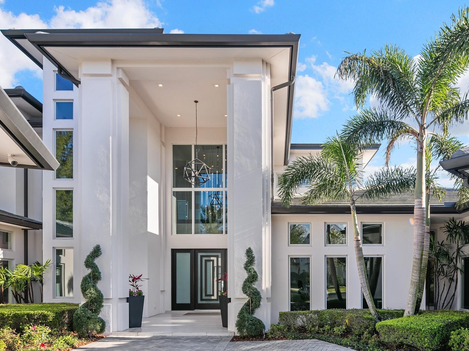 A masterpiece of artful design nestled in Windermere, Florida, this one-of-a kind,  Lake Burden home immediately transports you to a level of world-class beauty, serenity, and tranquility from the moment you enter. The home itself is a work of art, with exquisite attention to detail and a careful balance of form and function makes this oasis rare. The open concept living spaces flow seamlessly together, offering a sense of spaciousness and warmth. A dramatic double-height entry foyer leads you to an open concept floor plan featuring 11 ft ceilings, and Italian porcelain flooring throughout. The grand, masterpiece staircase connects two stories, appears suspended, carefully engineered with steel, glass and wood, immediately immersing guests in the home's meticulous design. Each room is thoughtfully programmed to create a harmonious yet functional atmosphere. The inviting living room fireplace, the spacious chef's kitchen features Miele & Wolf appliances,with an oversized eat-in waterfall island, quartz countertops and custom Busby cabinetry all against a spectacular backlit Onxy backsplash. The first floor primary suite is a true oasis, where every detail has been carefully curated to evoke a sense of calm with wide plank wood flooring, fireplace,  sitting area,  a spa-like walk-in shower, custom walk-in closet, and large dual vanities. There is also a secondary bedroom downstairs to accommodate your guests.  As you make your way upstairs, you will find two spacious bedroom suites and a fully equipped media room/game room with floor-to-ceiling glass walls.  Floor-to-ceiling automatic glass doors slide open to flood the interior with natural light, to seamlessly blend indoors and out while showcasing the breathtaking lake views of the surrounding landscape. Enjoy the bright living spaces, large two balconies and lounging sun deck while basking in the sun by the refreshing pool and spa tub outdoor area with lush landscaping and mature trees that provide privacy and seclusion. The indoor/outdoor living spaces are perfect for entertaining or intimately enjoying the surroundings.
 
Just a short drive from Disney World, Universal Studios and Sea World parks, world-class luxury shopping, fine dining, and entertainment, this private sanctuary in Orlando, is the perfect blend of luxurious elements, making it an ideal retreat for those seeking privacy and elegance.