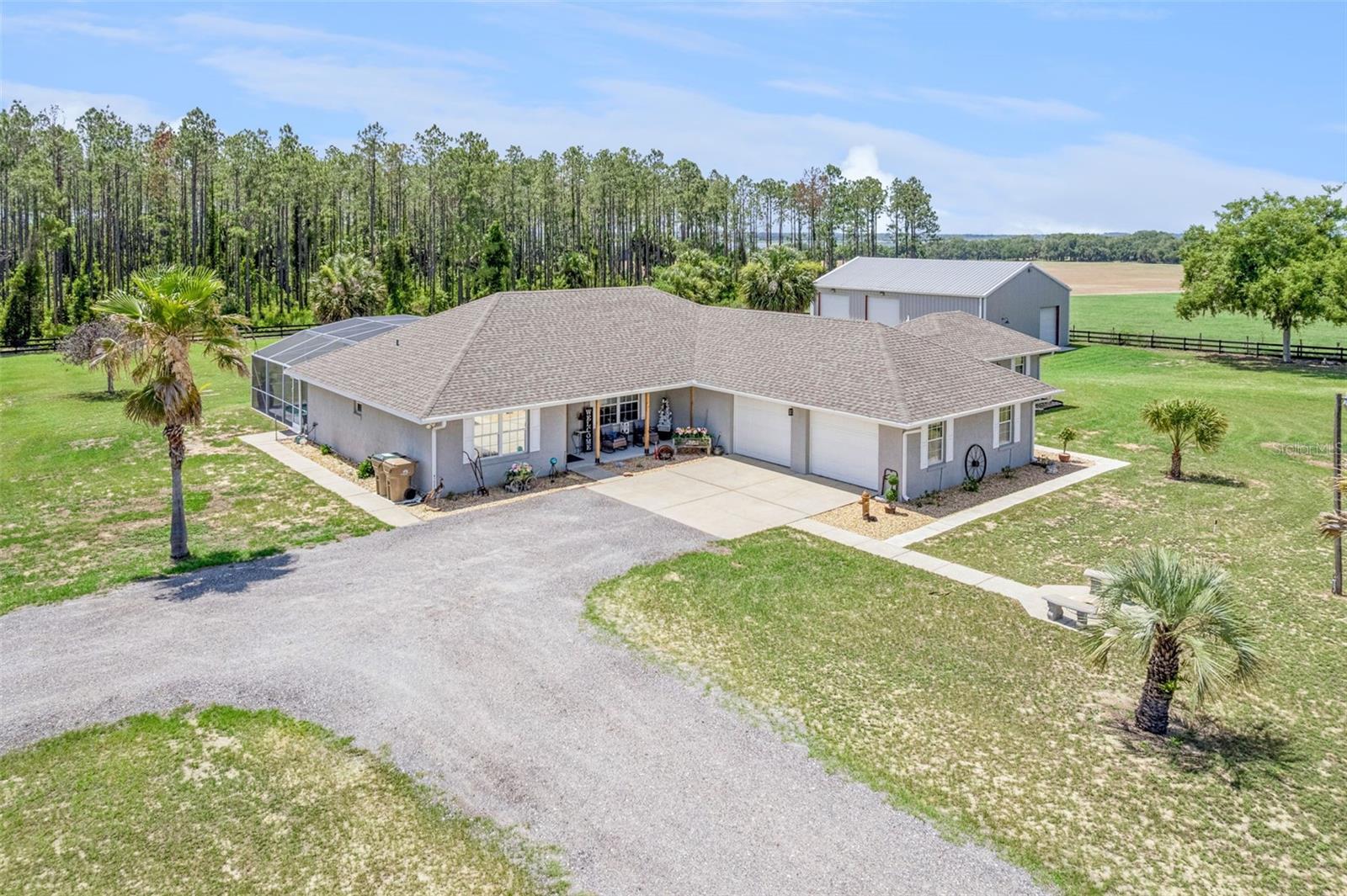 Welcome to your own private country retreat on 2.5 fenced acres, where comfort and peaceful living come together in one exceptional property. Conveniently located just minutes from Leesburg, Mount Dora, and The Villages, this unique estate offers the perfect balance of rural tranquility and modern convenience.

The beautifully maintained main residence features 3 bedrooms, 2.5 bathrooms, soaring ceilings, luxury vinyl plank flooring, abundant natural light, and an open-concept layout designed for everyday living. The kitchen is the heart of the home, showcasing granite countertops, custom cabinetry, stainless steel appliances, and a decorative tile backsplash. Additional highlights include abundant storage, an indoor laundry with utility sink, and an oversized attached 2-car garage.

Step outside to your own backyard oasis featuring a sparkling screened pool, expansive covered outdoor living areas, and an outdoor kitchen ideal for entertaining. Enjoy your morning coffee beneath the shade sail while taking in the sights and sounds of nature. Native wildlife, including blue jays, cardinals and sandhill cranes frequently visit the property, creating a peaceful setting.

A standout feature is the private ADU/in-law suite complete with its own kitchen, private entrance, full bathroom, stackable laundry, and flexible living space. Ideal for guests, extended stays, a home office, multi-generational living, or rental opportunities.

For entrepreneurs, hobbyists, and outdoor enthusiasts, the impressive 40x50 insulated red iron steel building offers 2,000 square feet of versatile space. Equipped with a half bath and utility sink, it provides ample room for vehicles, equipment, recreational toys, workshop activities, storage, and business operations.

The property features a private driveway, separate access to the workshop, and plenty of room for boats, RVs, trailers, horses, farm animals, and outdoor recreation. With no HOA, you'll enjoy the freedom to use the property your way.

Enjoy the serenity of country living without sacrificing convenience. Located approximately 10 minutes from Publix, 11 minutes from Lake Square Mall, 13 minutes from Home Depot, 30 minutes from The Villages, and about one hour from Walt Disney World.

Major improvements include a new roof in 2018 with upgraded CertainTeed shingles, updated electrical panels in 2018, a main house HVAC system replaced in 2015, and a new ac/heat wall unit installed in the ADU in 2025.

Properties offering this combination of acreage, a screened pool, detached workshop, private ADU, extensive parking, and modern updates are rarely available. Whether you're seeking a multi-use property, room for hobbies and equipment, or simply a peaceful place, this exceptional estate offers endless possibilities.

Main House includes refrigerator, range/oven, microwave, dishwasher (non-operational), disposal, and Alexa-controlled patio and outdoor lighting. Outdoor living area includes refrigerator, custom-built table, vintage 1950's drainboard sink, lighting, and sun sail. Firepit is optional; Blackstone, bar stools, and Adirondack chairs do not convey. ADU includes refrigerator, range/oven, microwave, and stackable washer/dryer. Shed included. Workshop includes utility sink and cabinetry; air compressor, car lift, tools, toolboxes, and storage shelves do not convey.

Photos have been enhanced to showcase dusk and evening lighting while remaining true to the property's appearance.