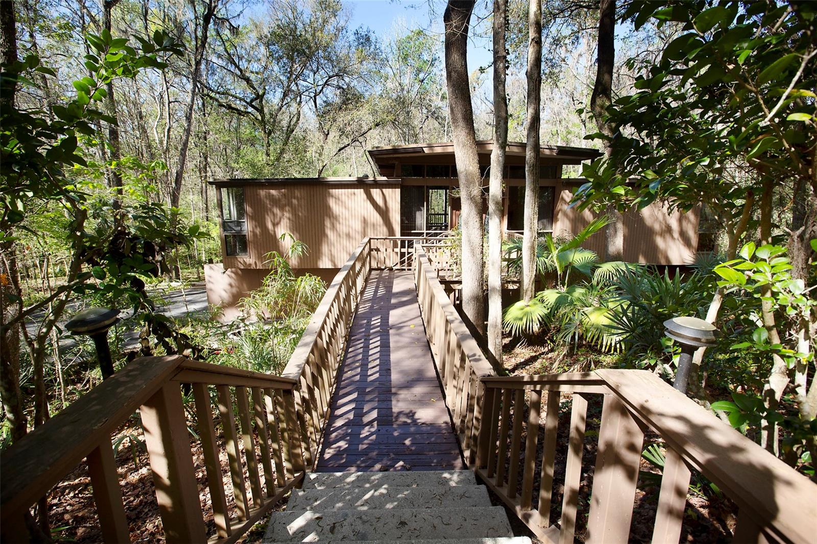A rare Gainesville retreat that feels like a mountain treehouse! Nestled on 1.38 private wooded acres in the highly desirable Maple Hill neighborhood, this one-of-a-kind contemporary home is tucked away along one of Gainesville's most scenic winding, hilly streets—yet is located just 2.5 miles from Ben Hill Griffin Stadium and the University of Florida.

Designed to bring the outdoors in, the home features soaring vaulted ceilings with exposed wood beams, walls of glass, and breathtaking views of the surrounding woods from nearly every room. The remodeled kitchen is beautifully appointed with quartz countertops, stainless steel appliances, and modern finishes while maintaining the home's distinctive architectural style.

The main level offers two bedrooms, including the primary suite, plus spacious living and dining areas that open to a large covered deck overlooking a crystal-clear creek below. The walkout lower level includes an additional bedroom and full bathroom, along with a second oversized family room—perfect for guests, a home office, or multi-generational living.

Outdoor living is just as impressive with expansive covered decks on both levels, creating peaceful spaces to relax, entertain, or simply enjoy the sights and sounds of nature. Additional features include a 2-car garage, generous storage room, and immediate availability for a one-year lease.

If you've been searching for something truly special, this home offers the serenity of a mountain retreat with the convenience of being just minutes from UF, shopping, restaurants, and everything Gainesville has to offer.

Available now for immediate occupancy. Owner is a licensed Florida Realtor.