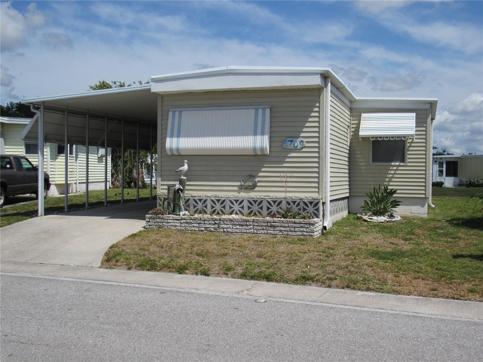 Welcome to Holiday Park, an active 55+, maintenance free, gated community! This very well maintained  2 bedroom, 2 bath home is being sold furnished turnkey and ready for you to move right in! In addition there is a 20 x 11 Florida Room with screens and vinyl windows plus an additional 17 x 11 inside laundry/storage/workshop room with screens and vinyl windows..  There are newer laminate floors in the living room, dining room, and primary ensuite bedroom.  The kitchen has an abundance of raised panel cabinetry, The recreation facilities in this community include 2 heated pools, shuffleboard, clubhouse with a library, meeting rooms, fitness center. and tennis courts. The low monthly maintenance fee is included in the tax bill. All of this and just minutes to shopping, dining, fishing, golf and more!
