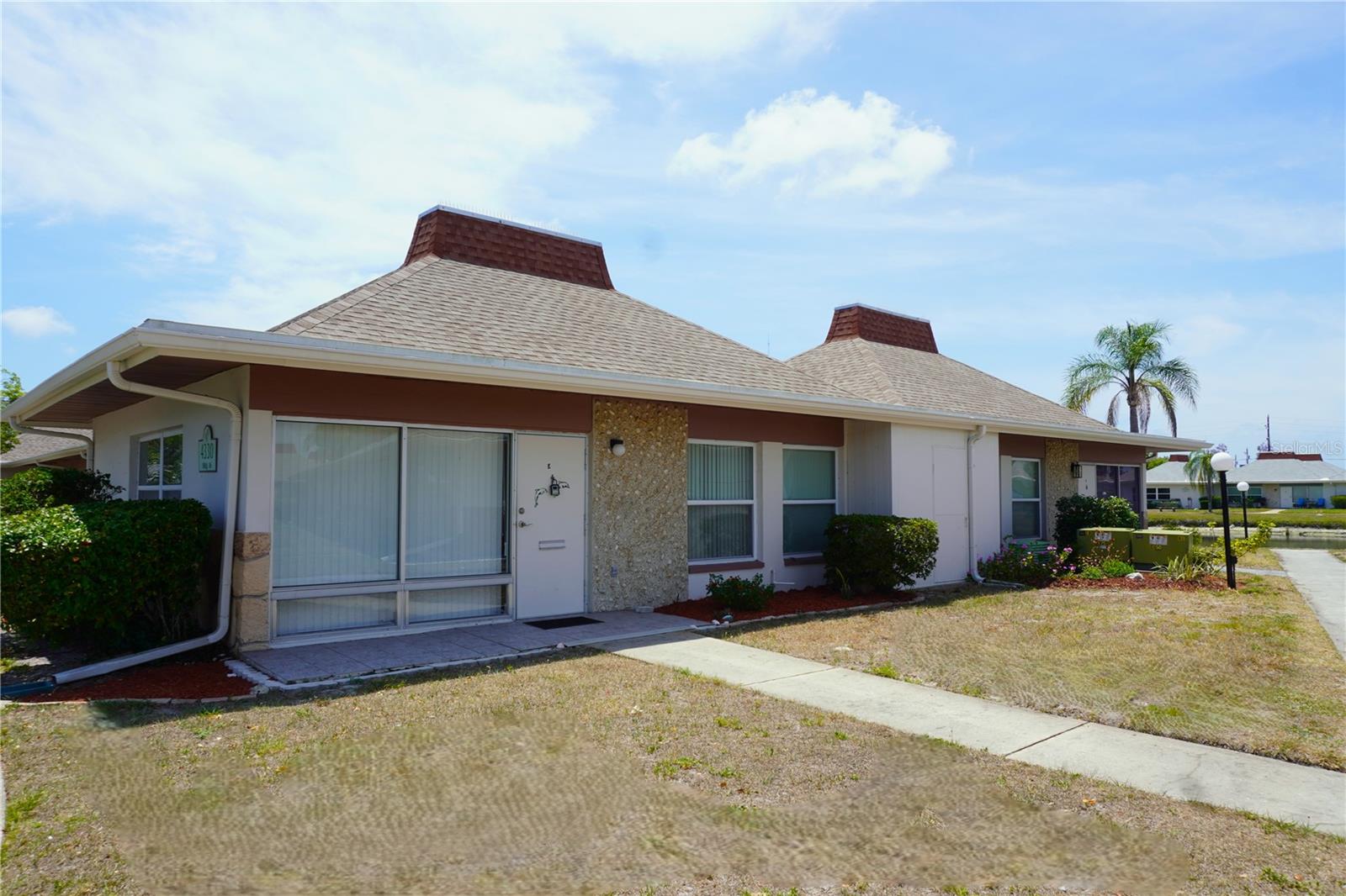 Discover this UPDATED and meticulously maintained corner unit in the serene 55+ gated community of Tahitian Gardens. This 2-bedroom, 1 and 1/2 bath residence is ideal for both part-time and full-time living in Florida. Step into the living room and appreciate the cross-cut tile flooring, open floor plan, and abundant natural light. The kitchen boasts updated cabinets, a spacious dining area, and stainless-steel appliances. The main bathroom features a full-sized walk-in shower and additional storage cabinets. Other enhancements include storm windows, a large washer/dryer, newer roof and an updated electric panel.  Enjoy a partial lake view from your private patio. Tahitian Gardens offers amenities such as a heated swimming pool, shuffleboard courts, and two community buildings for a variety of activities and events. Located near Tarpon Springs' historic district, shopping, dining, and Florida's beaches. This home is a testament to the owner's pride and meticulous care. Schedule your viewing today.