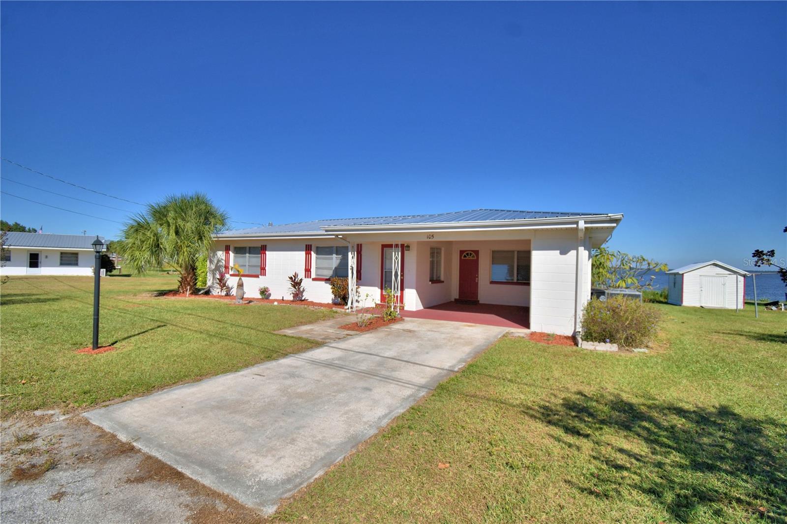 Lakefront home on Lake Reedy.  This 3 bedroom 1 bath concrete block home has a brand new metal room.  (Oct. 2025).  105' of lakefront with 2 slip boat dock.  The dock is 65' long with landing is 15 X 16 so plenty of room for fishing or relaxing and watching the sunrise.  There had been power at the dock.  Updates to the home include electrical with 200 amp panel, plumbing updates in the bathroom, Carrier AC installed around May or June of 2025.  Irrigation well has new pump but owner has never used the irrigation.  Special features are gas stove in the kitchen with small tank and lake view, gutters, city water and sewer, storage shed with new roof, enclosed back porch, and landscaping.  The back open porch is 12 X 4 with hand rail and steps leading out to the dock.  Terrazzo flooring throughout, some rooms have been freshly painted, laundry is in the one car carport, the large 23 X 12 enclosed back porch affords amazing views of the lake with windows on 3 sides.  See video link
