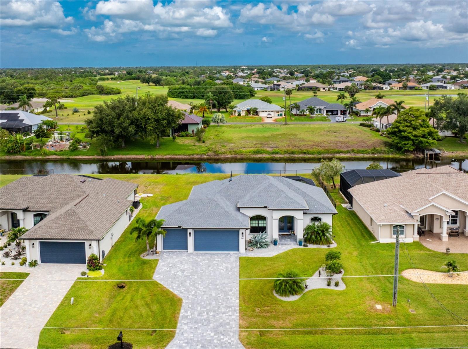 Experience the best of Florida waterfront living in this exceptional 2024 Breakwater Construction residence, where stunning canal views, a heated saltwater pool, and an oversized 3-car garage create an unparalleled lifestyle. Featuring 3 bedrooms, 2 bathrooms, and quality construction throughout, the structure is located in the desirable X flood zone for added peace of mind. From the moment you arrive, the welcoming curb appeal is evident on the oversized lot with a paver driveway and walkway, tropical landscaping, and architectural details highlighted by a multidimensional roofline and blue accent colors that perfectly complement the home's contemporary design. Double glass entry doors topped with a transom window open to an expansive great room where a quadruple set of 16-foot pocketing sliders completely disappear from view, seamlessly blending indoor and outdoor living while truly bringing the outdoors inside. Woodgrain tile flooring flows consistently throughout the home, while coffered ceilings with crown molding, designer paint colors, and abundant natural light create a warm yet sophisticated atmosphere. The open-concept design seamlessly connects the living, dining, and kitchen areas. The kitchen serves as the heart of the home, featuring modern wood cabinetry with soft-close drawers and doors, illuminated glass-front high upper cabinets, under-cabinet lighting, a contrasting white island, granite countertops, and an extended walk-in pantry offering an abundance of storage. The formal dining area is perfect for gatherings and entertaining. The spacious primary suite offers a relaxing retreat with a tray ceiling accented by crown molding, dual walk-in closets, and a beautifully appointed ensuite bath featuring a fully tiled walk-in shower and dual granite-topped vanities. Two guest bedrooms include reach-in closets and are conveniently located near the guest bath, which offers a tiled tub and shower combination along with a granite-topped double vanity, providing ample space for guests. The large laundry room includes built-in shelving and a utility sink with granite countertop. Additional highlights include a well-fed irrigation system, preplumbed for an outdoor kitchen, blown-in insulation in the attic, a garage that is portable generator ready, a 9-foot third-car garage door, and epoxy-coated garage floors. This home also has the option to be purchased with furnishings. Step outside to the extended, partially covered paver lanai where panoramic screening provides unobstructed views of the canal and local wildlife without blocking the scenery, allowing you to enjoy the outdoor living space in virtually any weather. The heated saltwater pool with waterfall feature is perfect for relaxing and entertaining. Pet lovers will appreciate the fenced backyard area. Located within the deed-restricted community of Rotonda West, residents enjoy access to five premier golf courses, miles of scenic lakes and canals ideal for fishing and wildlife viewing, tennis and pickleball courts, walking and biking trails, social clubs, and a variety of community activities. Gulf beaches, parks, shopping, restaurants, waterfront tiki bars, boat ramps, medical facilities, and more are all within ten miles. Baseball fans will appreciate the nearby spring training facilities for two Major League Baseball teams. Whether seasonally or year-round, this exceptional residence offers the very best of the Rotonda West lifestyle.