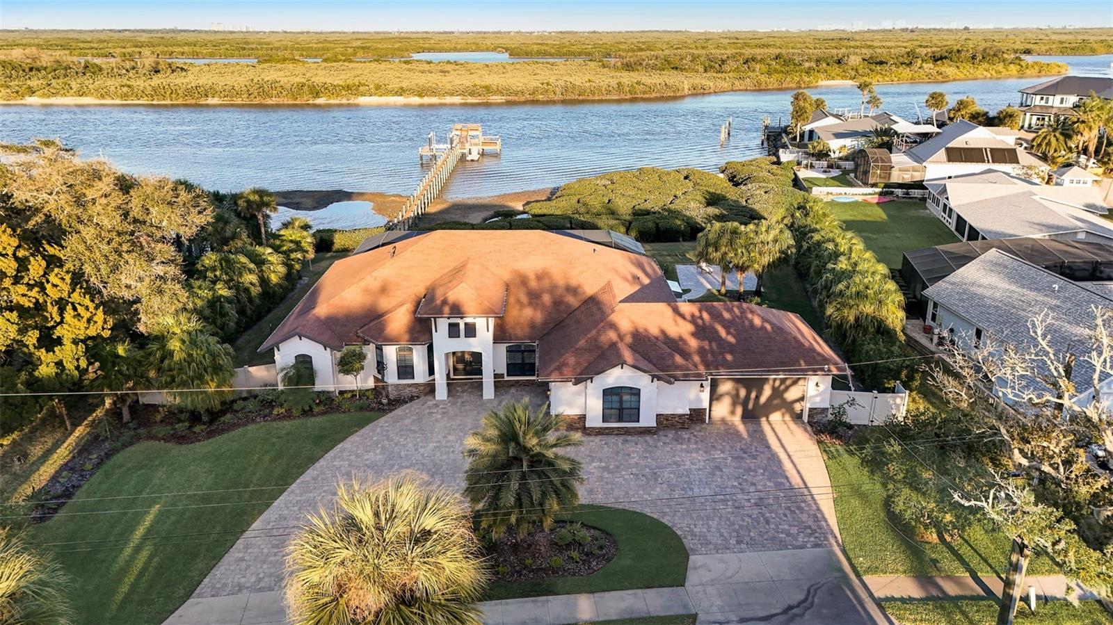 This exceptional waterfront property nestled in a private cove boasts over 1/2 acre and over 175 ft on the main channel of the prime direct Intracoastal waterway. This is the epitome of the quintessential Florida lifestyle. Whether you seek a vacation residence, retirement haven, secondary home, permanent dwelling, or investment property, look no further – your dream is on the verge of becoming a reality.

Approaching this exquisite abode, you'll immediately notice the elegantly sealed paver driveway and meticulously landscaped surroundings. The oversized climate controlled 3-car garage with epoxy floor finish, impact windows, and freshly painted exterior complete the picture of perfection. Upon entering through the front door, prepare to be enchanted. The unobstructed panoramic view of the Intracoastal waterway spans right from your own backyard. The sheer beauty of this sight is truly awe-inspiring, transforming this property into a breathtaking masterpiece that you can call home.

The interior showcases gorgeous teak flooring throughout most of the main living area, while the kitchen boasts lovely tile to encapsulate its charm. The grand living room is a haven of luxury, offering unbelievable river views. A stunning coffered ceiling adds to the opulence, while hurricane-rated sliding doors open fully and pocket into the walls, seamlessly merging the outdoors with the interior living space. Feel like a part of the party as you create culinary masterpieces in the "gathering room" (also known as the kitchen). Whether you choose to gather around the granite countertop, enjoy a meal in the breakfast nook, or dine formally in the dining room sipping water fresh from your very own whole house water purification system, there is ample space for everyone. Stainless steel appliances, including a gas range, abundant granite countertops, an extensive pantry, and ample cabinetry to accommodate even the most extensive collection of cookware, make this kitchen a chef's paradise.

The generous-sized bedrooms offer comfort and functionality, while the mother-in-law suite affords breathtaking river views. The captains quarters not only provide easy access to the pool area but also feature a walk-in closet that doubles as a safe room. There is a whole house generator. Step outside onto the expansive screened in 2,600 sq ft patio and pool area. Relax in the 18x30 self-cleaning pool, luxuriate in the hot tub, or unwind on the couch while enjoying your favorite movie and the warmth of the gas fireplace. Not only are there two covered seating areas, but there is also a full summer kitchen complete with a gas hook up. Beyond the screened enclosure, you'll discover a 550 sq ft paverd courtyard, cared for garden and 12x12 greenhouse with electric and water. Immerse yourself in the beauty of the surroundings as you take a leisurely stroll down the 280 ft long dock, featuring two levels, a floating dock, a fish cleaning station, and amenities such as electric, water, 13,000 lb boat lift, and seating areas. Can you imagine watching a space launch from the comfort of your pool? It's an experience like no other!
Make this extraordinary property your new home.