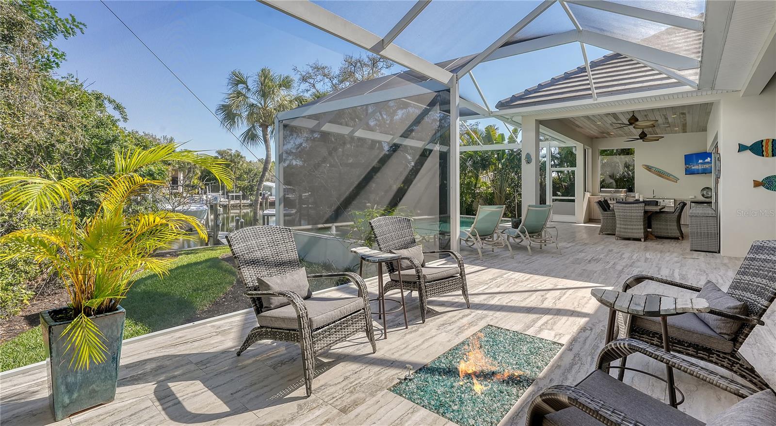 Indulge in the epitome of waterfront luxury living at this exceptional custom-built residence on Siesta’s grand canal, a five-minute boat ride to open water. Crafted by NC Ferguson with meticulous attention to detail and completed in 2017, this three-bedroom plus office home blends sleek contemporary finishes with comforting style, offering peace of mind with recent hurricane specifications, including impact windows, sliders, doors, and high elevation. Nestled on an oversized waterfront parcel, this home welcomes you with lush landscaping, a pavered driveway, and a spacious three-car garage equipped with an electrical car charging receptacle. Step inside the nearly 2,600-square-foot interior to discover a sprawling great room layout, with its gourmet kitchen, open dining, and living area all adorned with Italian Argento travertine flooring that extends onto the outdoor terrace, creating a seamless indoor-outdoor living experience. The chef’s kitchen is a culinary dream, featuring quartz countertops, a 10’ island with extra thick quartz countertop, high-end Miele appliances including a built-in coffee station and natural gas cooktop, custom Irpinia cabinetry, designer lighting, and two pantries for ample storage. Pocketing sliding glass doors in the living/dining room bring the outdoor spaces inside, while a gas fireplace adds warmth and ambiance. Convenient electric shades offer effortless control of light and privacy, and the main living space easily converts to a home theater with its hidden, remote-controlled projector and screen. Retreat to the luxurious owners' suite, where Caribbean-inspired styling meets modern comfort. Wood floors, tray ceilings, and disappearing corner sliders create a serene atmosphere, while a walk-in closet spanning 16-feet, with custom built-ins, offers abundant storage. The accompanying spa-like bath features double sinks with LED motion sensor vanity mirrors, a water closet with bidet, and a walk-in shower designed for relaxation. The adjacent office provides a convenient workspace. Two additional bedrooms and inspired quartz bathrooms ensure comfort for guests or family members. Step outside to discover an outdoor paradise, complete with private canal views, a summer kitchen, dining and lounge areas, a heated pool with sun shelf and spa, built-in fire pit, outdoor shower, newer dock with Trex decking, and a 6,000-pound boat lift, ideal for exploring Siesta Key’s sparkling waterways. Located within walking distance to Out of Door Academy and moments away from Siesta Key beach, this home offers luxury, convenience, and island living. Siesta Key's vibrant community boasts its own nearby Village with shopping, parks, and family-friendly activities. Just minutes away, downtown Sarasota beckons with its array of activities, fine dining, and shopping options.