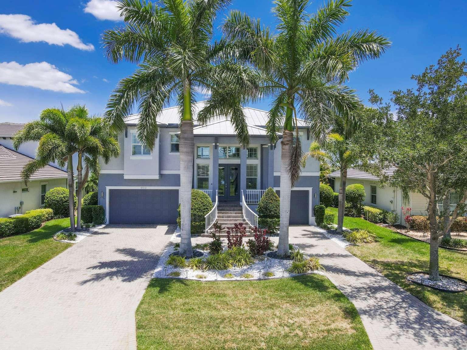 Breathtaking, completely remodeled riverfront home in Tidewater Preserve, a luxury boating community on the Manatee River. This nearly 4,000 sq ft residence offers 3 ensuite bedrooms, 3.5 baths, extended 3-car garages, soaring ceilings, hurricane windows, metal roof, and sweeping river views. The open second-floor great room features a coffered ceiling, built-in TV wall with 96-inch fireplace, floating cabinets, quadruple sliders, surround sound, and built-in bar. The remodeled gourmet kitchen includes a 48-inch stainless commercial 6-burner gas cooktop with griddle, commercial hood, Cambria quartz counters, waterfall island, full-height backsplash, custom cabinetry, walk-in pantry, stainless appliances, built-in oven, and wine refrigerator. The primary suite includes river views, custom walk-in closets, and a spa-style bath with dual sinks, soaking tub, walk-in shower, and Cambria finishes. Downstairs includes two additional ensuite bedrooms and a large den/great room with built-in queen Murphy bed. Outdoor living includes upper and lower covered lanais, oversized automated saltwater pool and spa, outdoor kitchen, panoramic two-story screen enclosure, and a custom spiral outdoor staircase connecting both levels. Tidewater Preserve amenities include private marina, tennis courts, resort-style pools, riverfront trails, fitness centers, amenity centers, kayak and paddleboard storage and launch, dog park, and 24-hour guard-gated security.